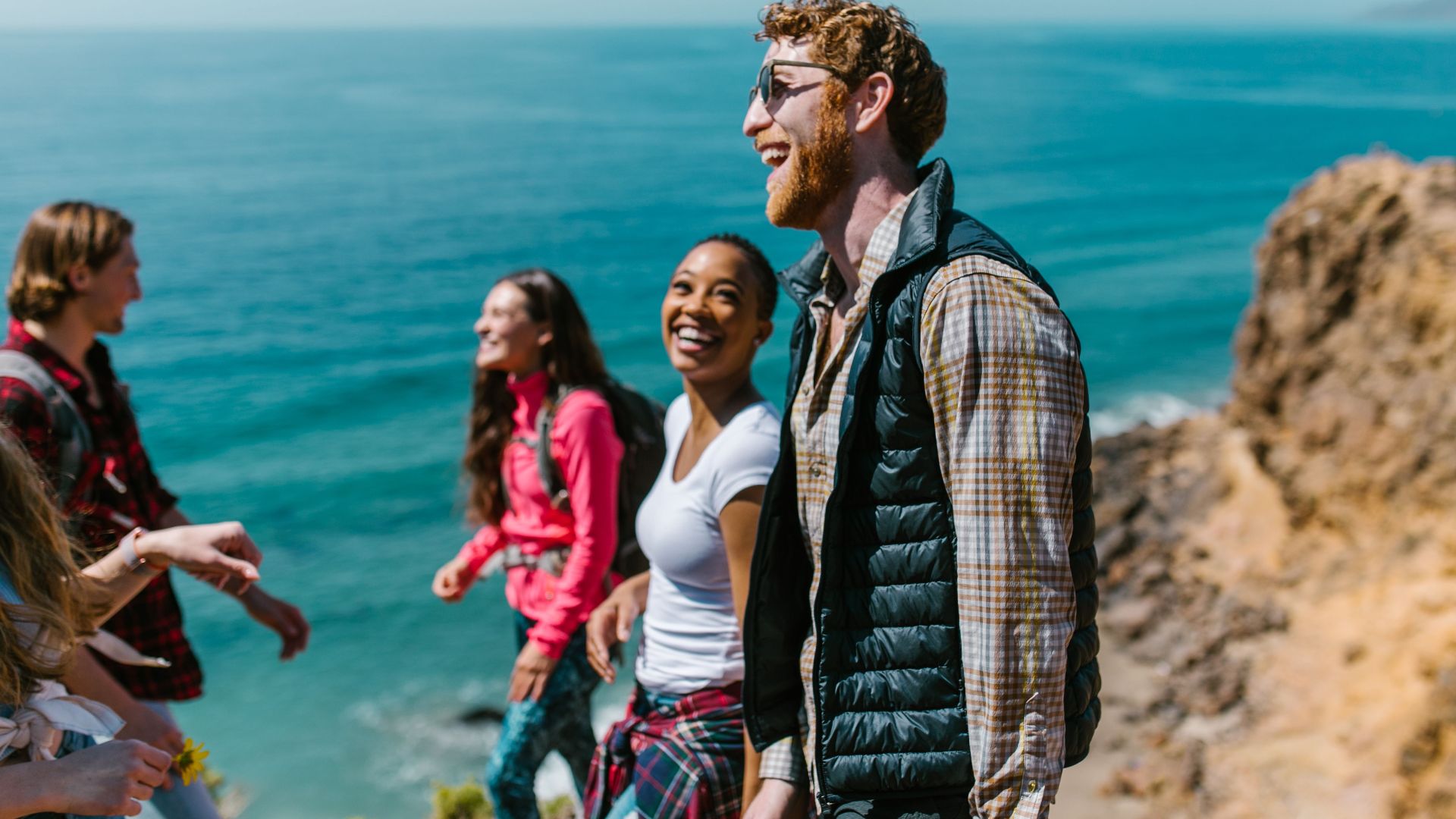 A joyful group of friends hiking along a scenic coastline, enjoying laughter and good company.