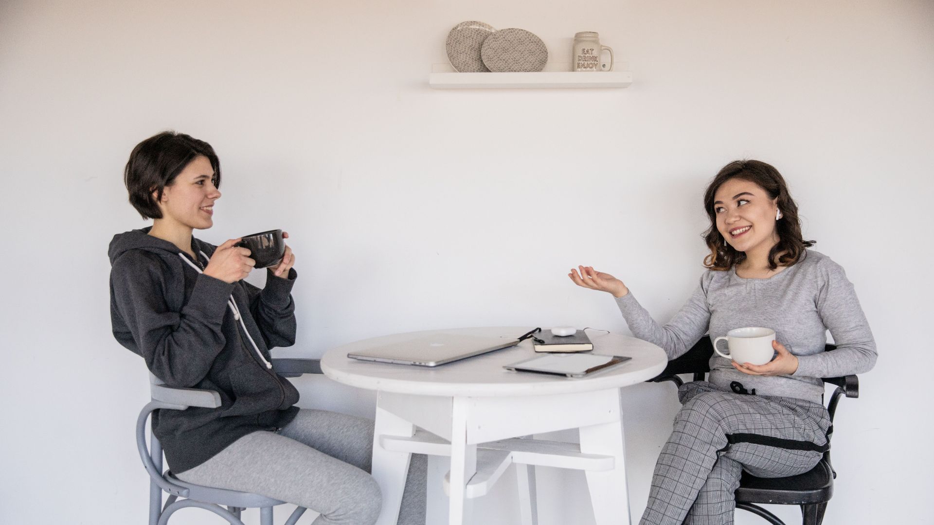 Two women enjoying a friendly chat over coffee indoors, relaxed and smiling.