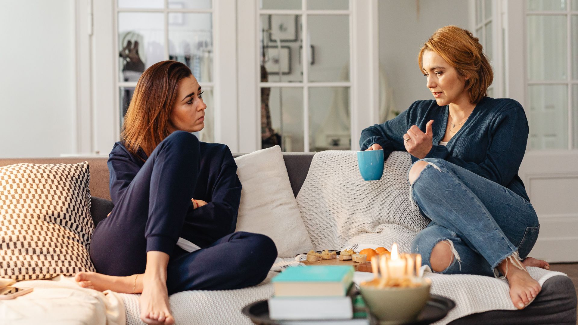 Two women having a heartfelt conversation, enjoying a cozy moment in a modern living room.