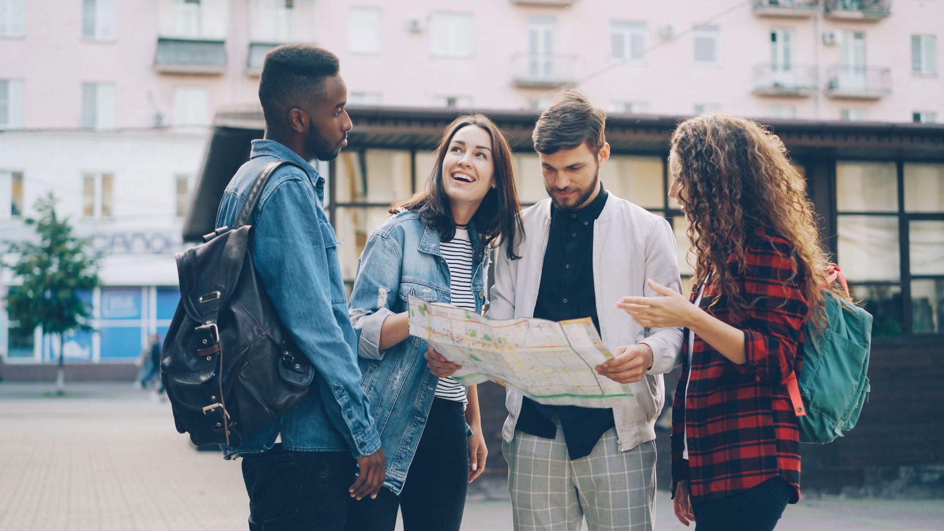 Four young friends reading a map outdoors, planning their city adventure.