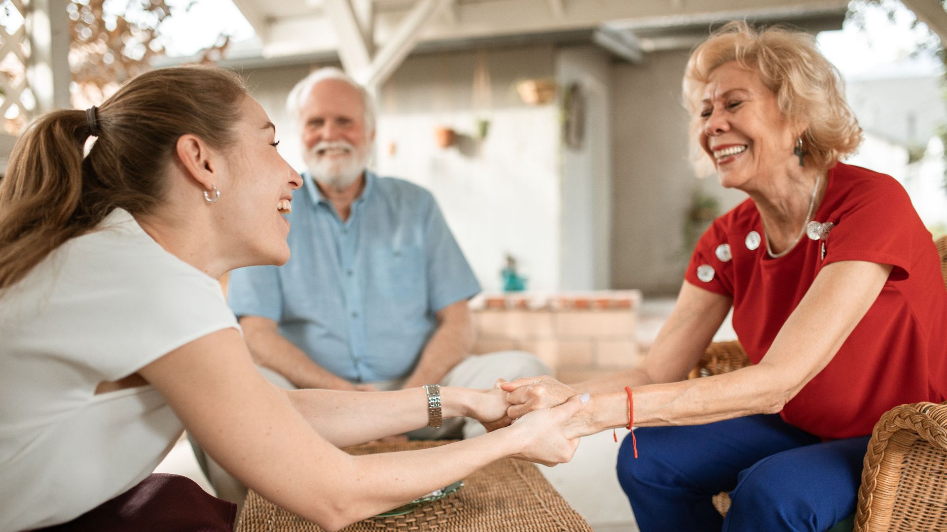 Three family members enjoying a happy conversation outside, sharing laughter and smiles.