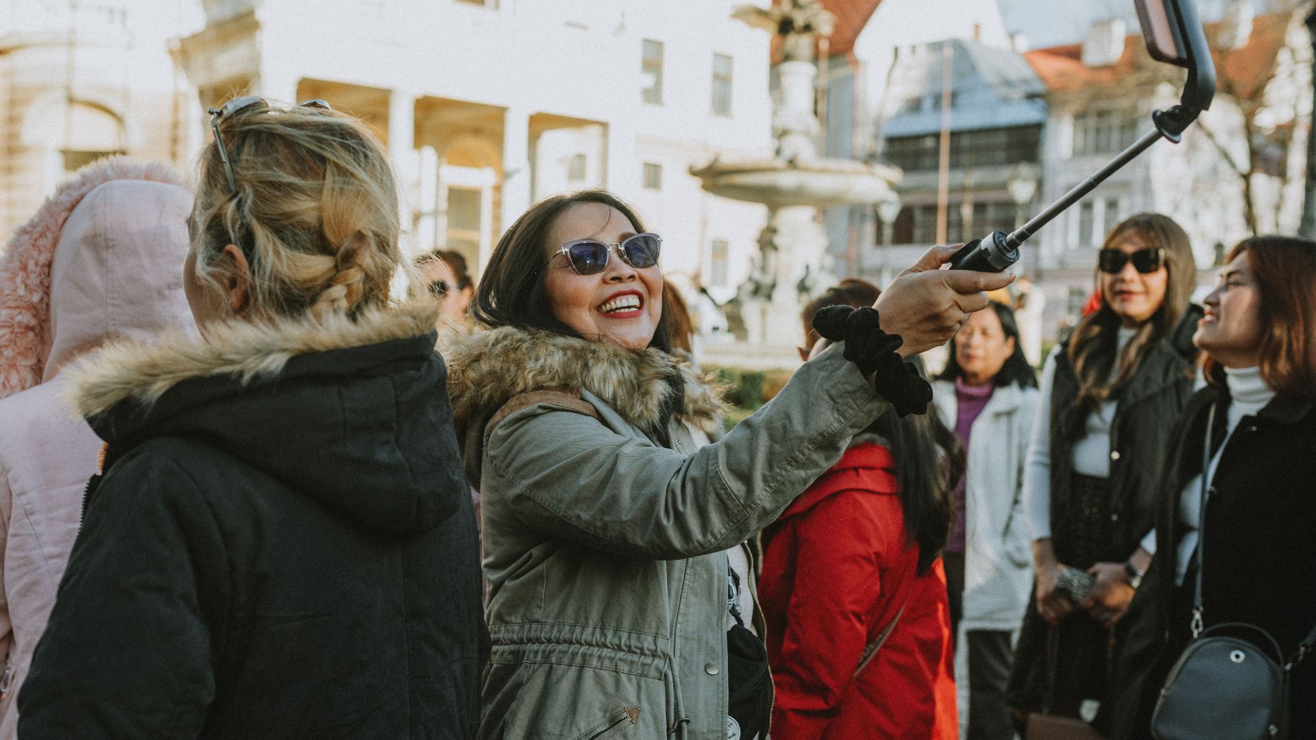 A group of tourists enjoys a city tour, capturing memories with a selfie in an urban setting.