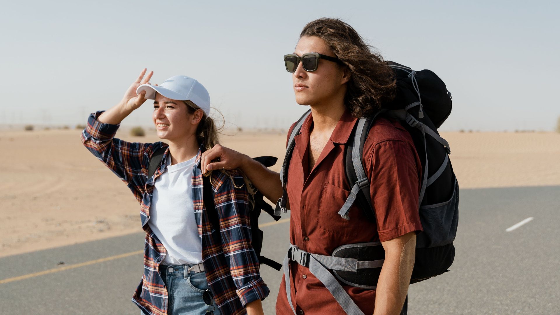 Young couple backpacking through a desert road, capturing wanderlust and exploration.