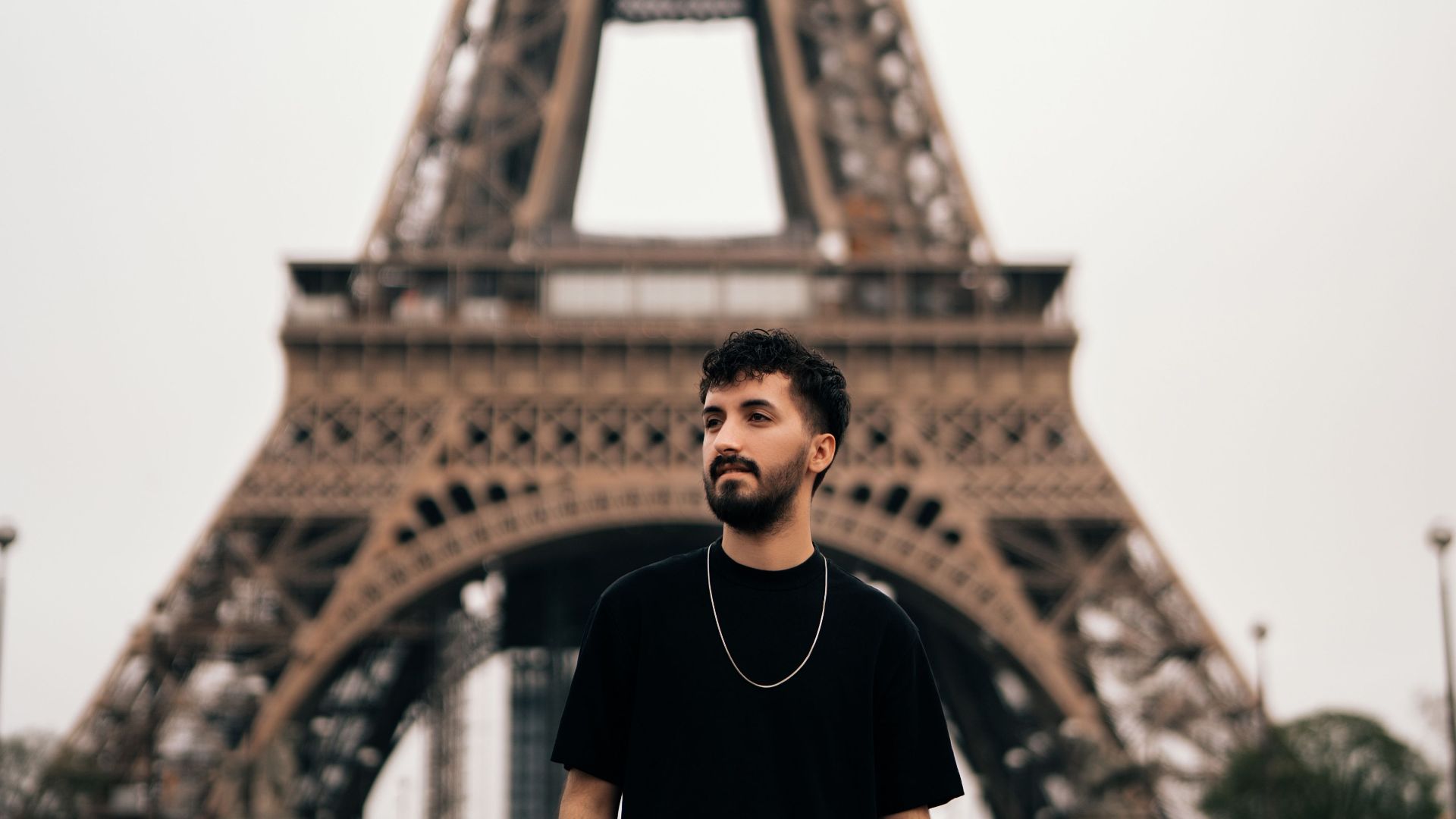 A young man stands in front of the Eiffel Tower, capturing an iconic Paris moment.