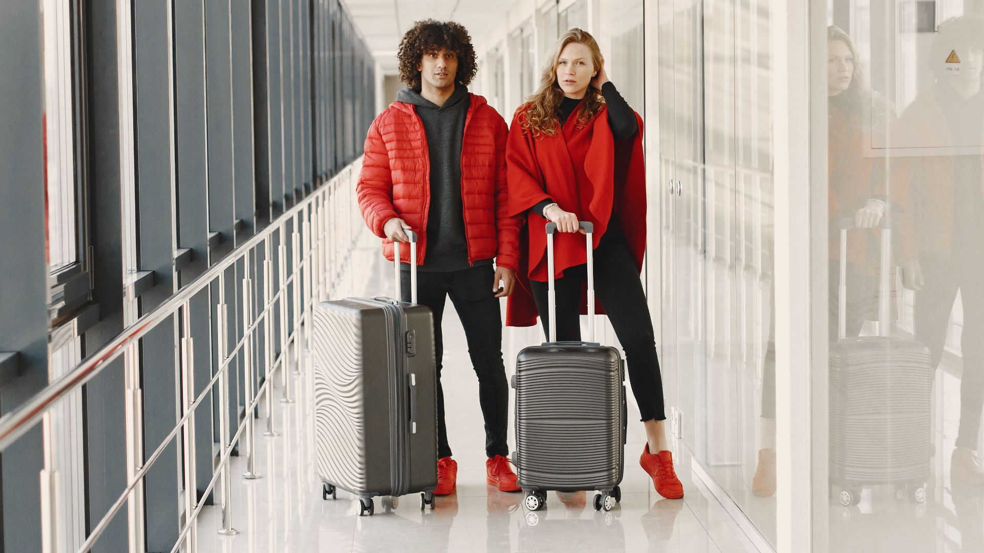 Young couple standing in a hallway with luggage, ready for travel. Bright modern scene.