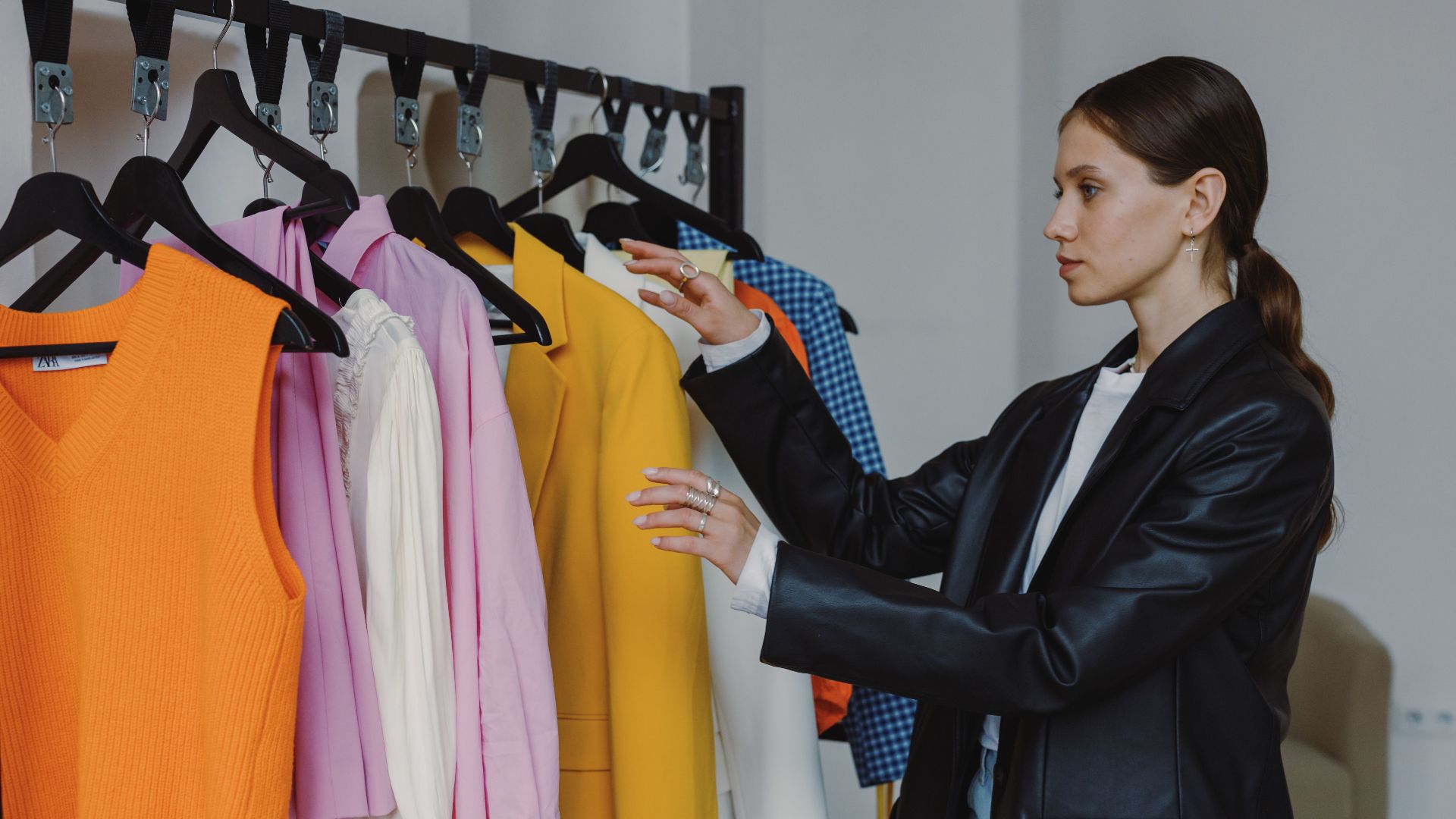Side view of a woman browsing colorful fashion collection in a modern store.