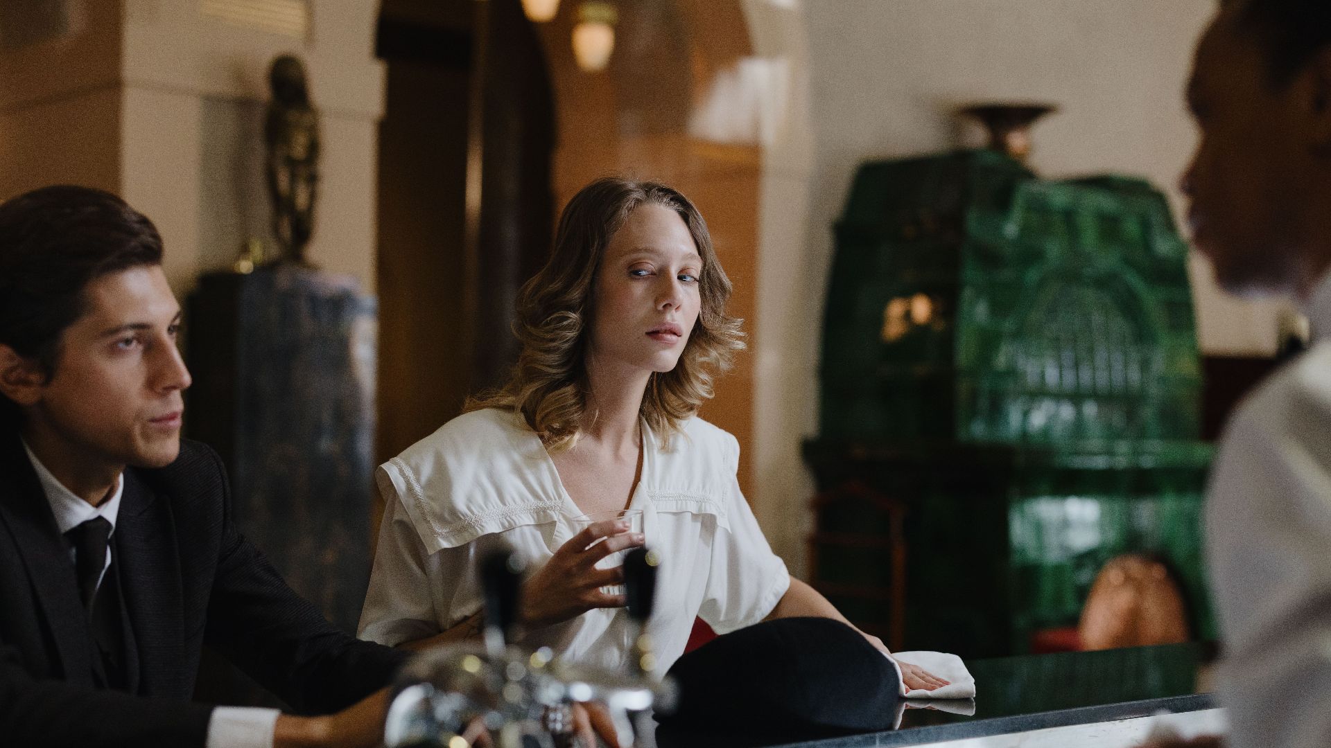 A retro-style bar scene with elegantly dressed individuals conversing indoors.