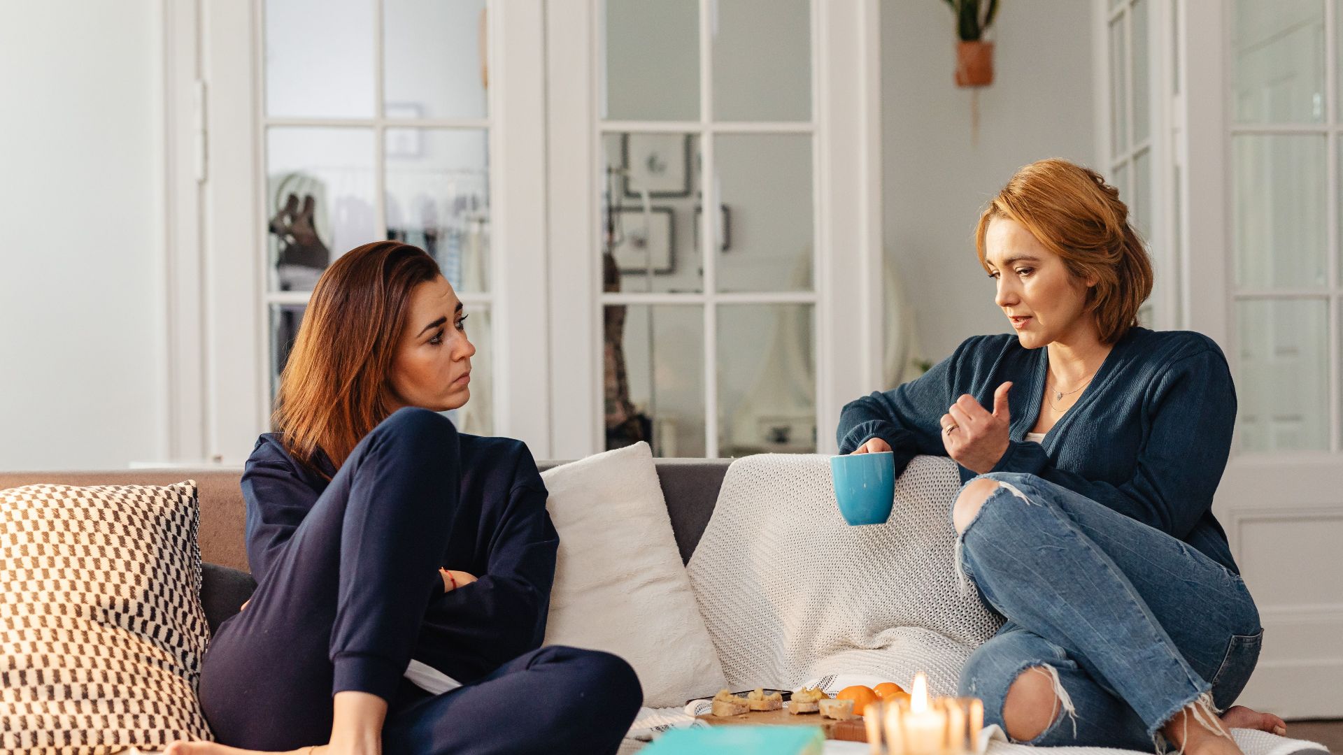 Two women having a heartfelt conversation, enjoying a cozy moment in a modern living room.