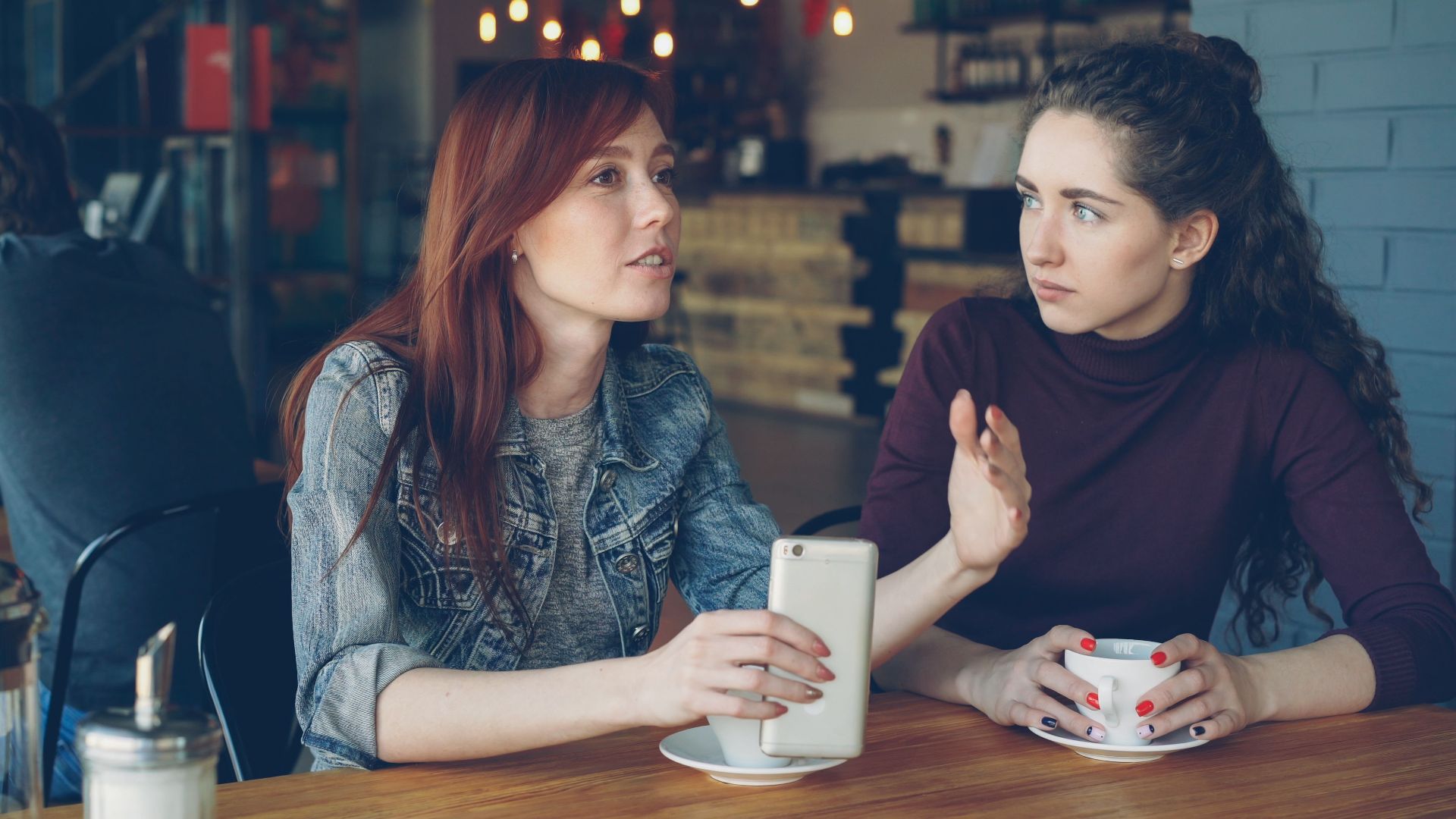 Two young women having a conversation over coffee in a cozy café.
