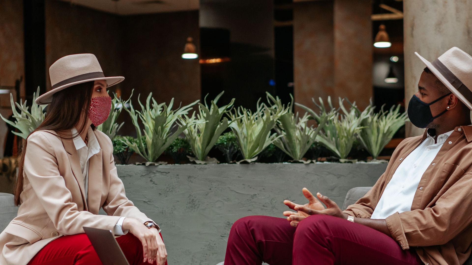 Caucasian woman and Black man meeting in hotel lobby wearing face masks.
