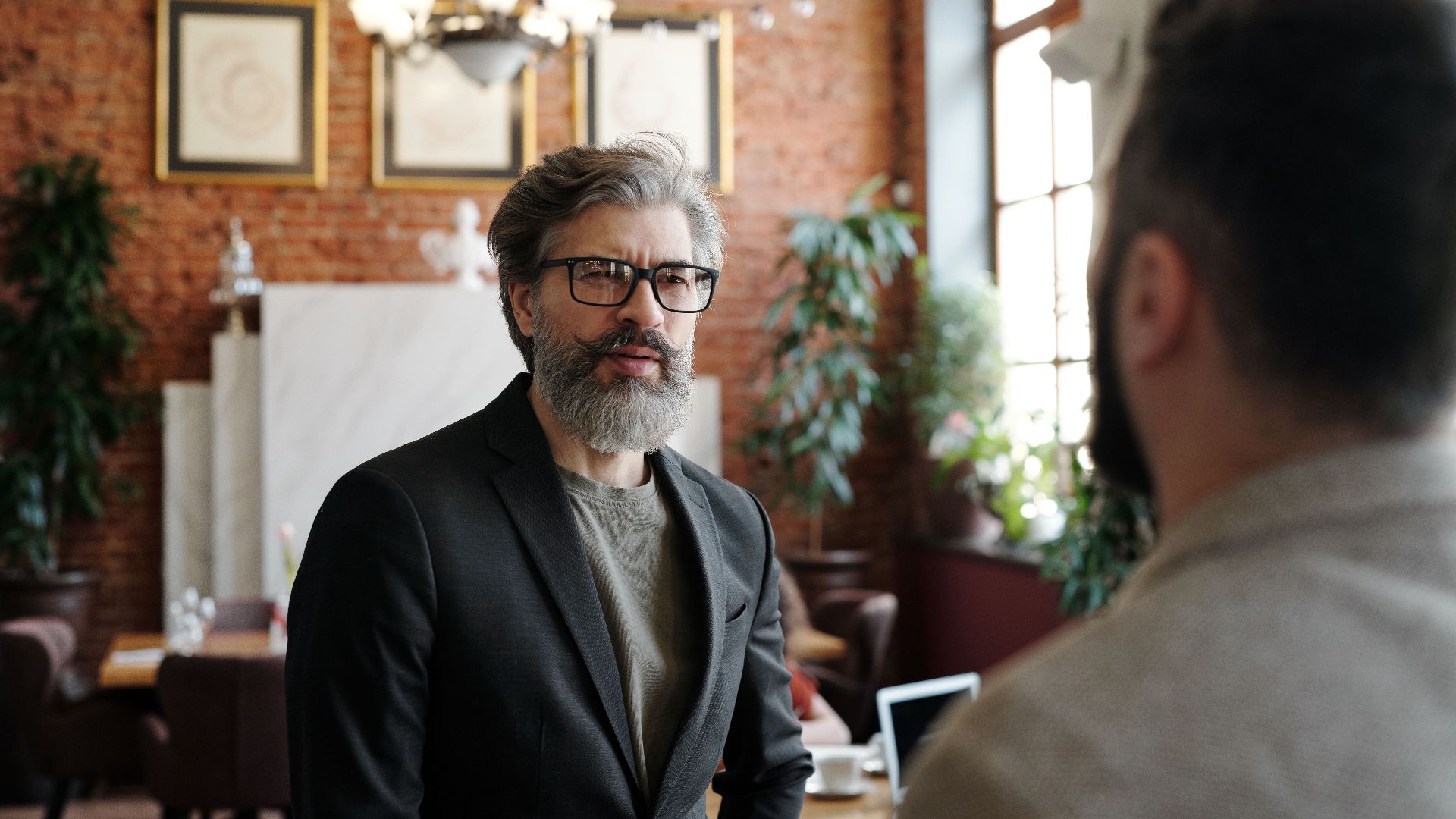 Senior man in suit with beard and eyeglasses in a business setting.