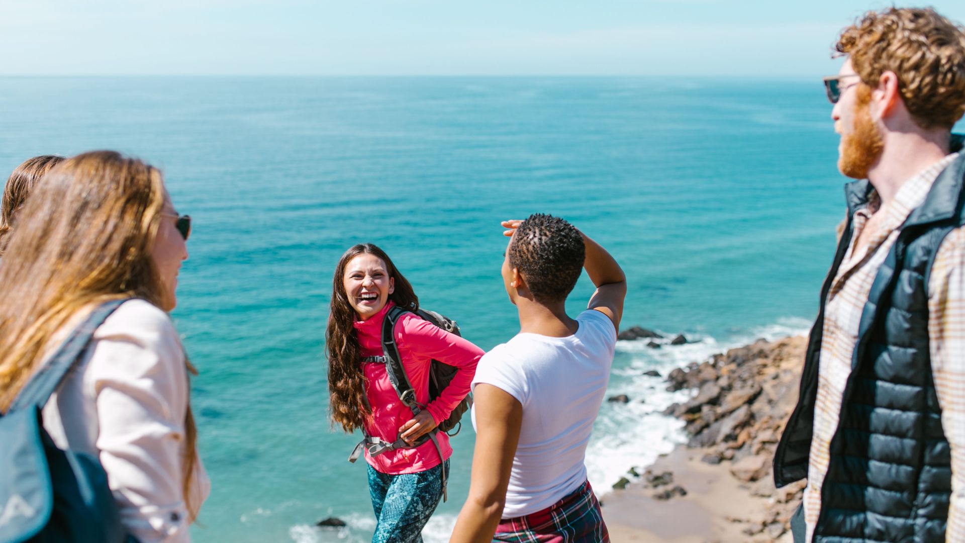 A joyful group of friends hiking near the ocean, enjoying the scenic view.