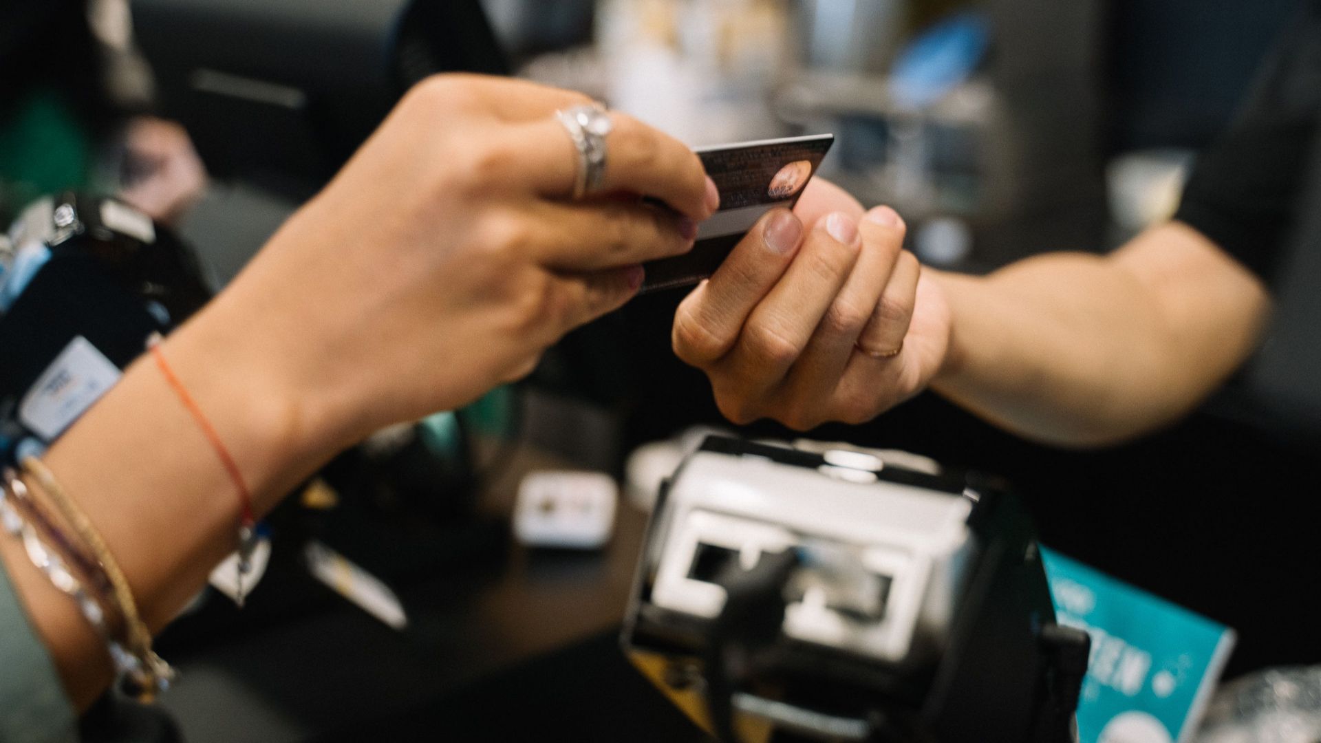 Close-up of hands completing a payment transaction at a retail checkout using a bank card.