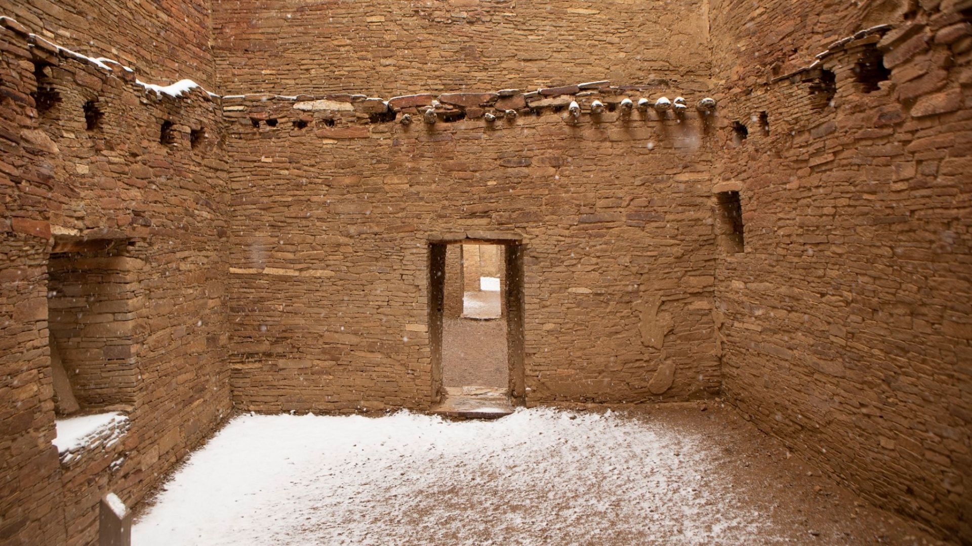 An interior shot of Pueblo Bonito showing tall sandstone walls and snow on the ground.
An exposed room of Pueblo Bonito with snow.