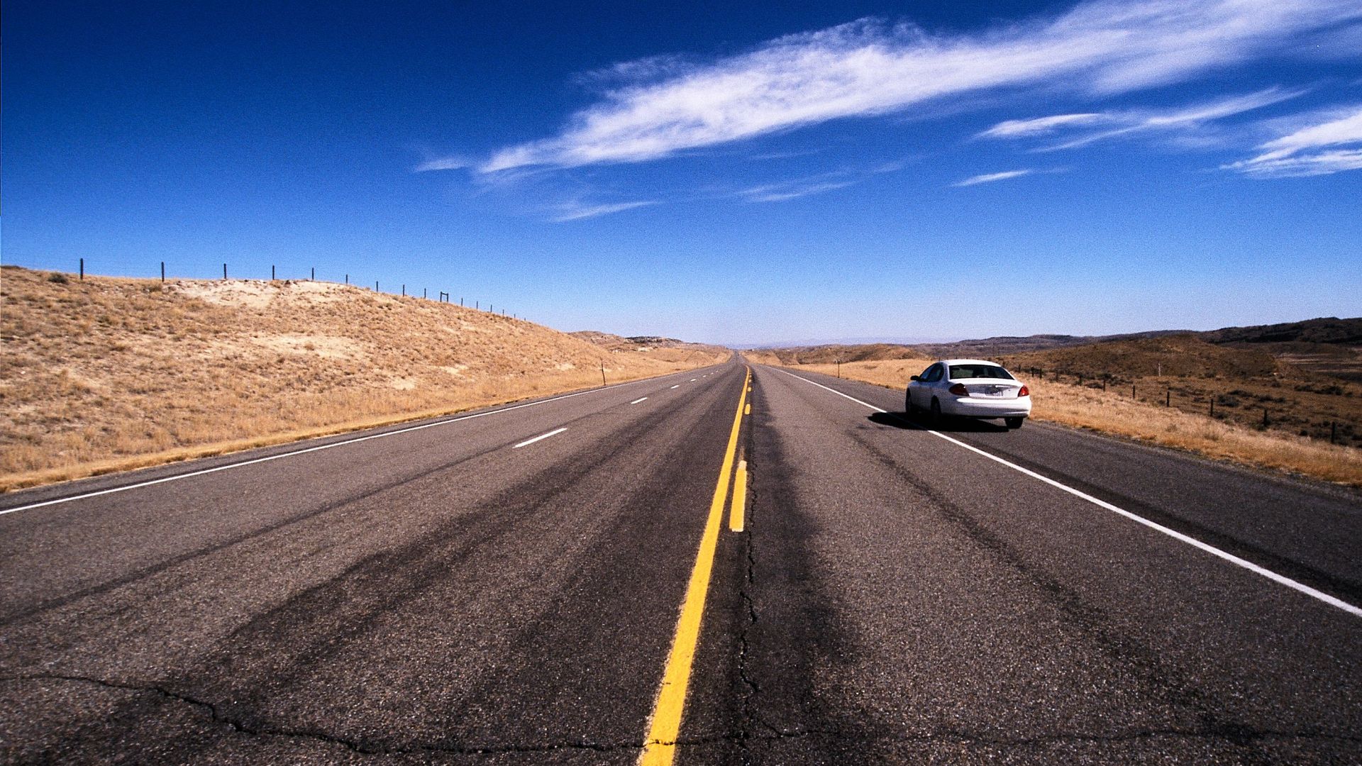 Explore the vast open road in Wyoming under a clear blue sky.