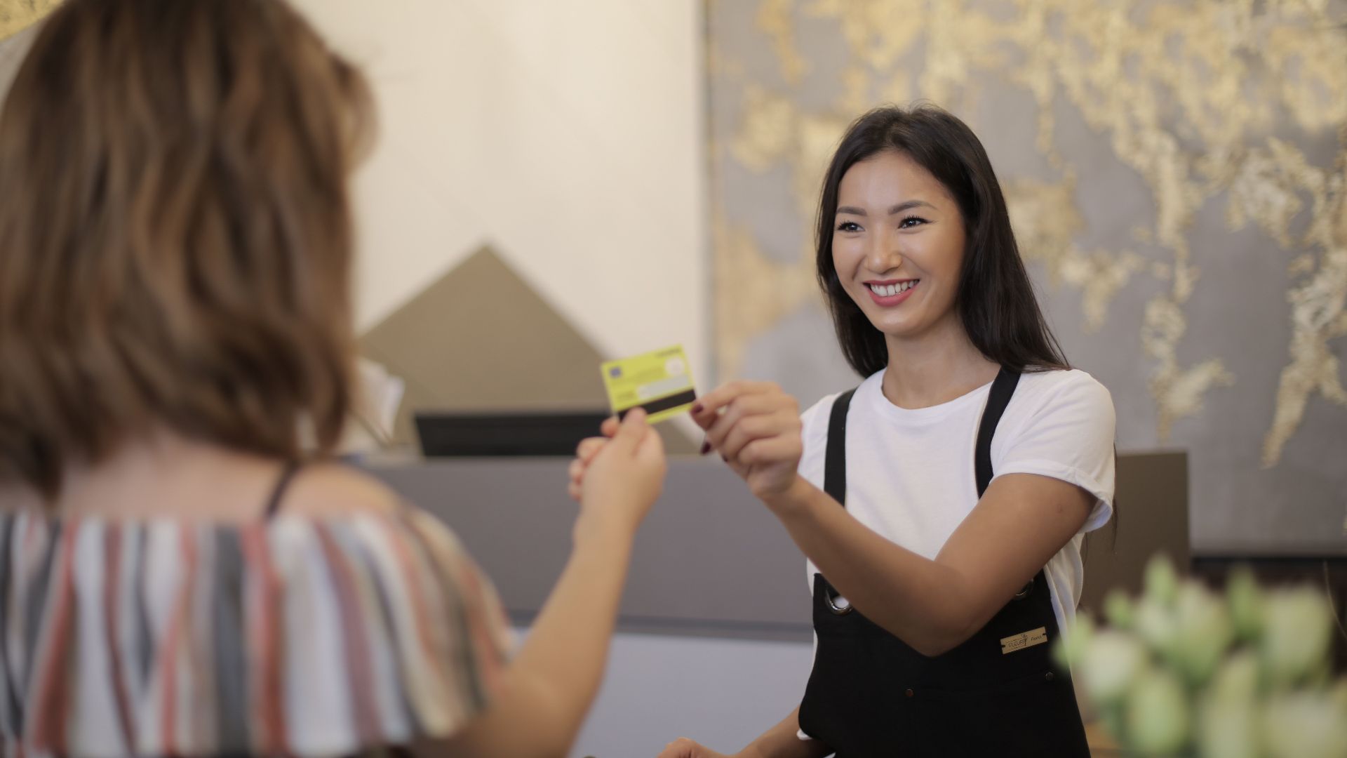 Florist smiling while accepting payment in a flower shop.