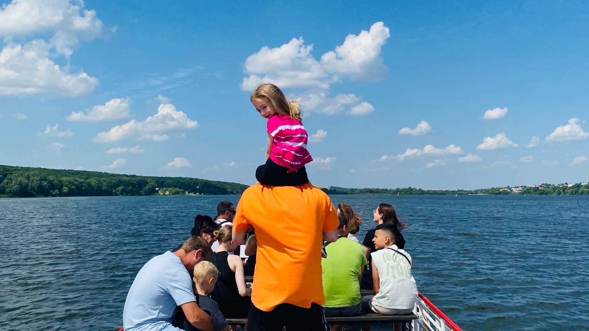 Family group enjoying a scenic boat ride on a sunny day, perfect outdoor relaxation.