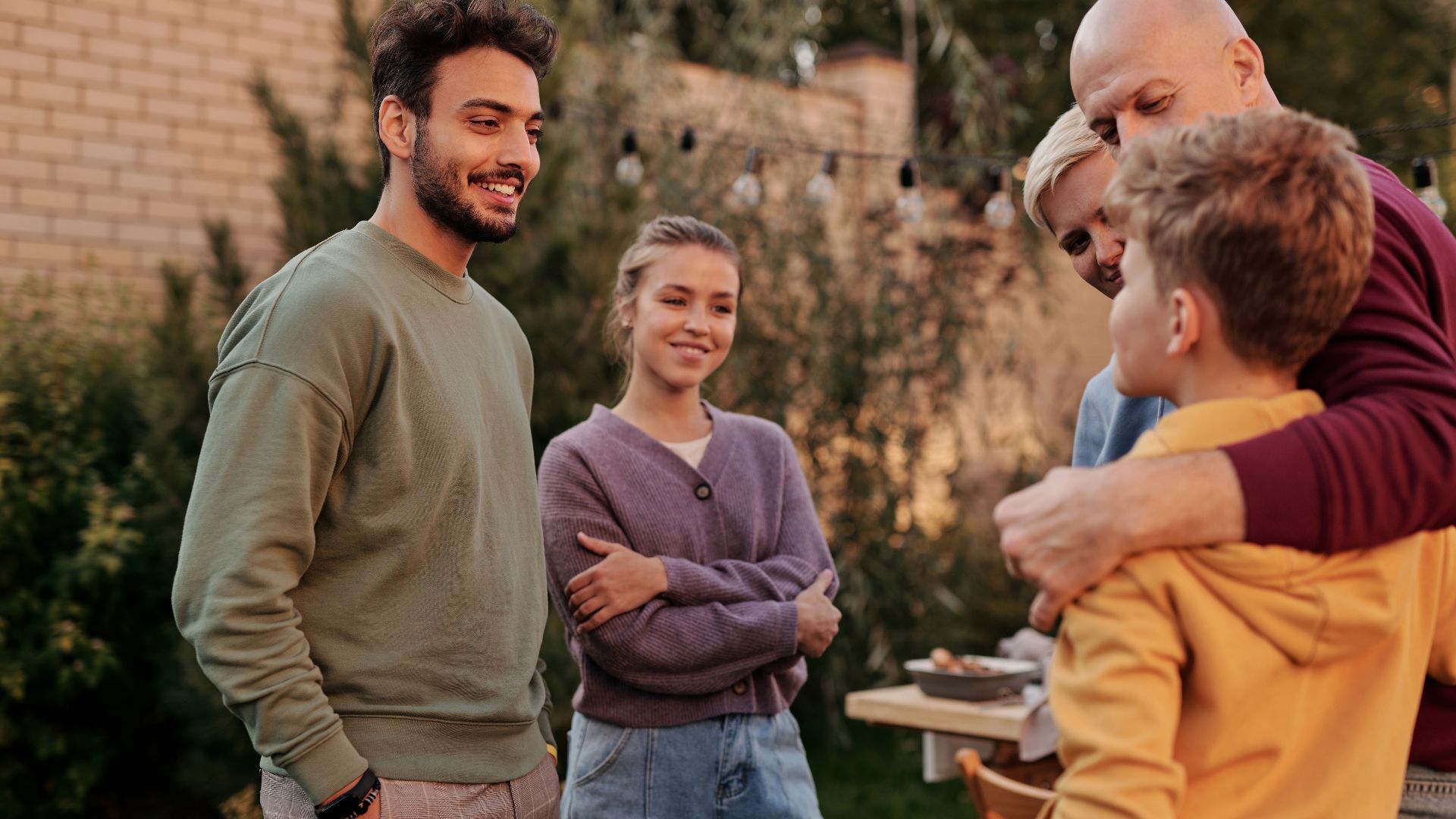 Group of cheerful multiracial relatives smiling and communicating in yard during meeting in summer weekends