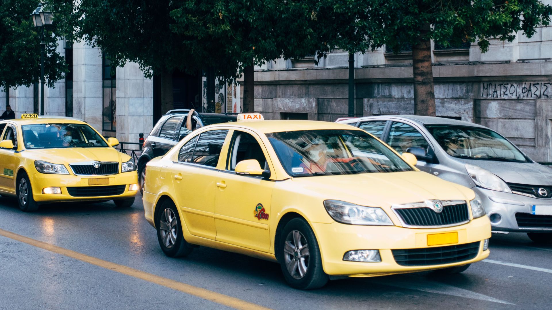 Yellow taxis lining the street in Athens, Greece, showcasing city's bustling transportation.