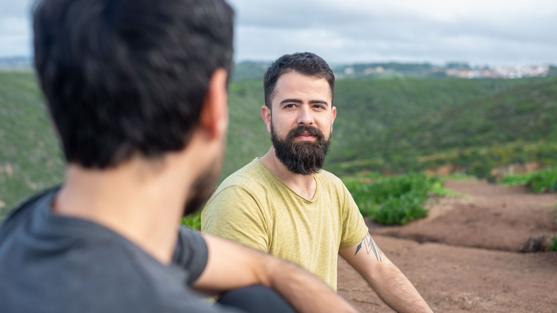 Two men sitting on a hillside in Portugal, enjoying a relaxed conversation.
