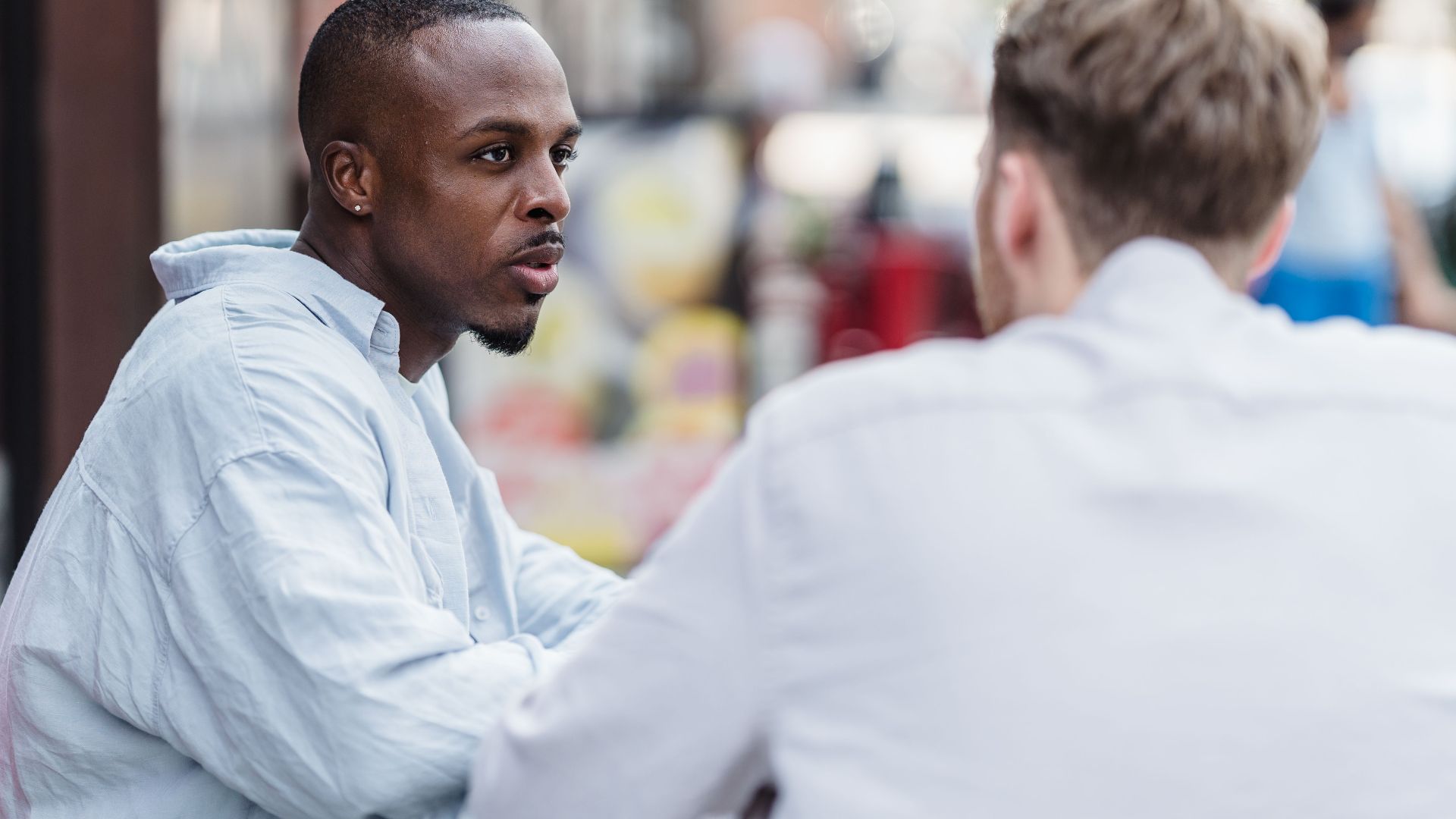 Two men having a conversation in an outdoor setting on a sunny day.