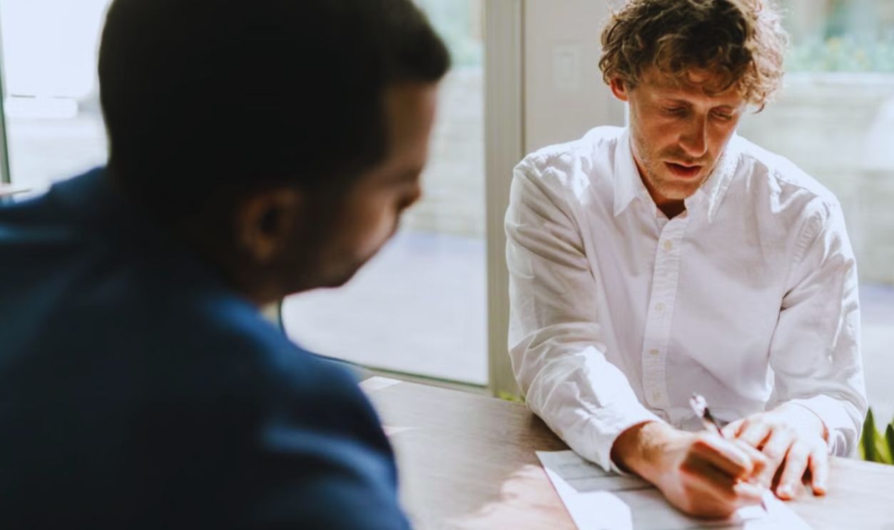 Two men collaborating in a modern office, reviewing and signing documents