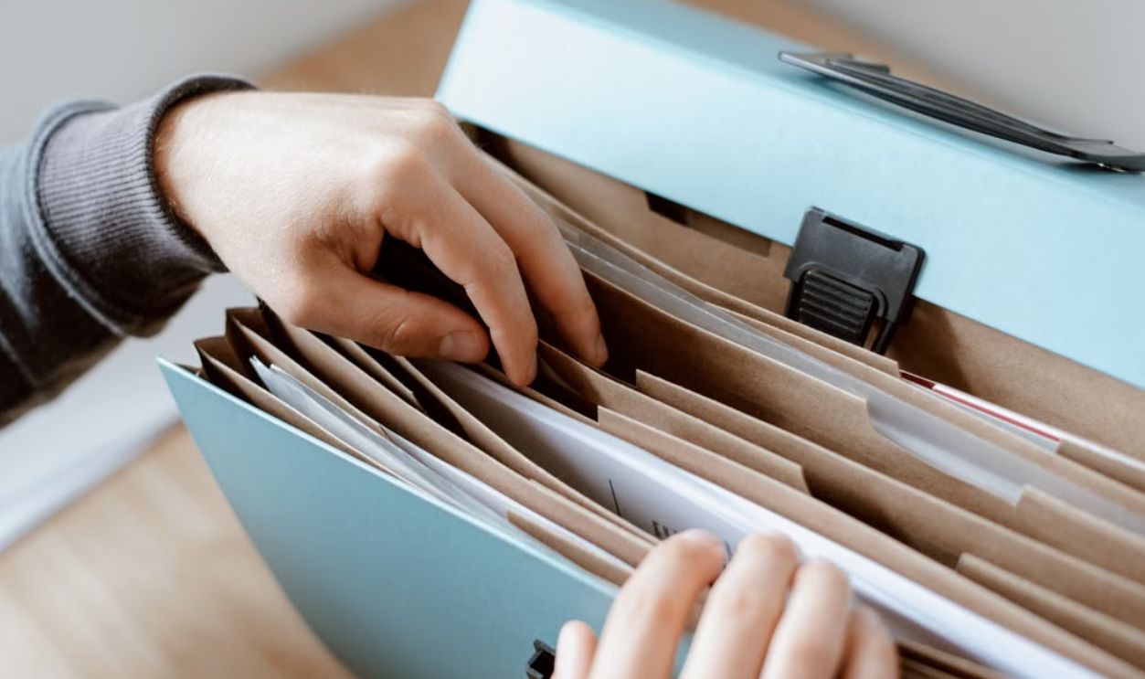 Close-up of hands organizing papers in a blue folder, ideal for business and office concepts