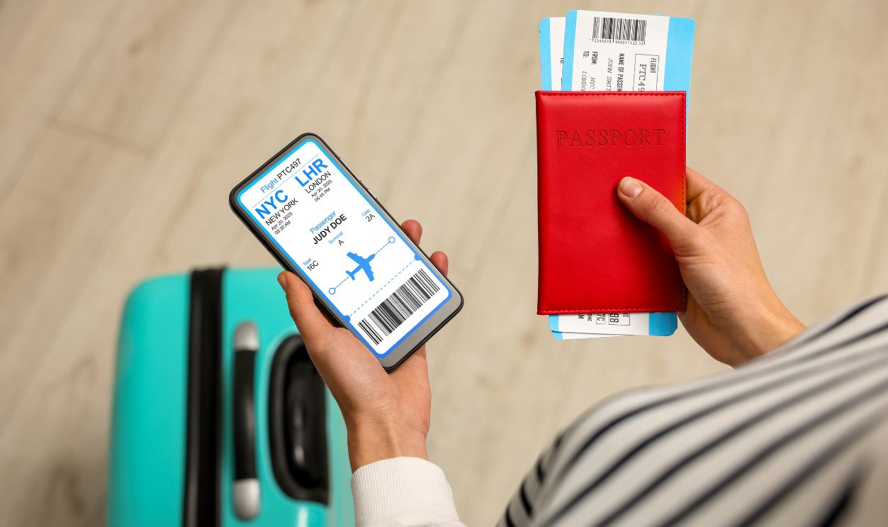 Tourist holding mobile phone with e-ticket for airplane and passport indoors, closeup