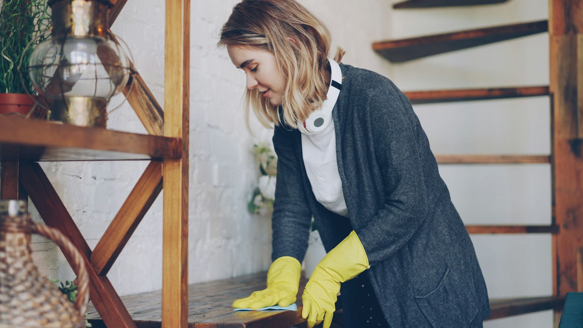 Woman wearing yellow gloves cleaning wooden surface