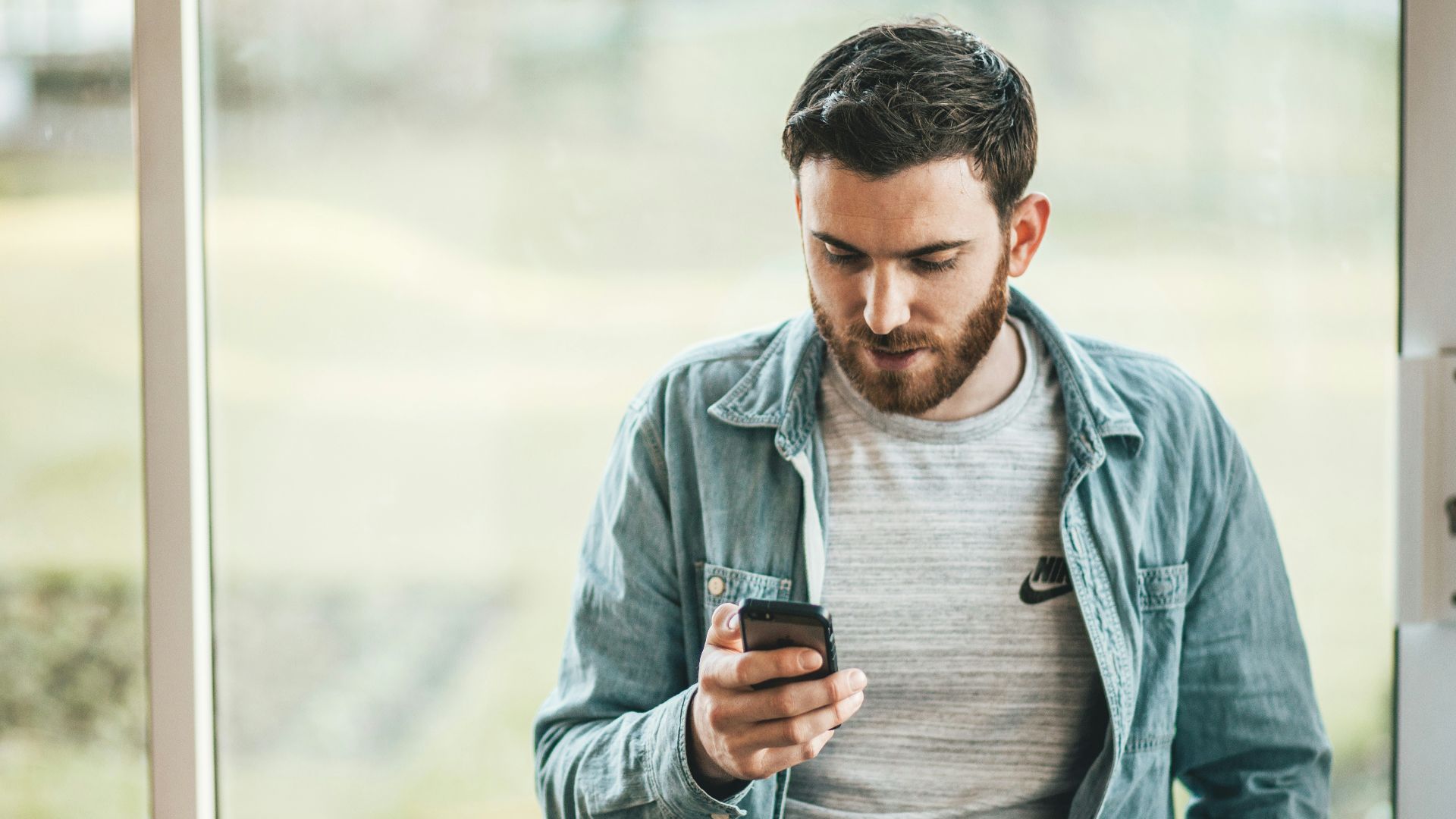man holding a smartphone near the window