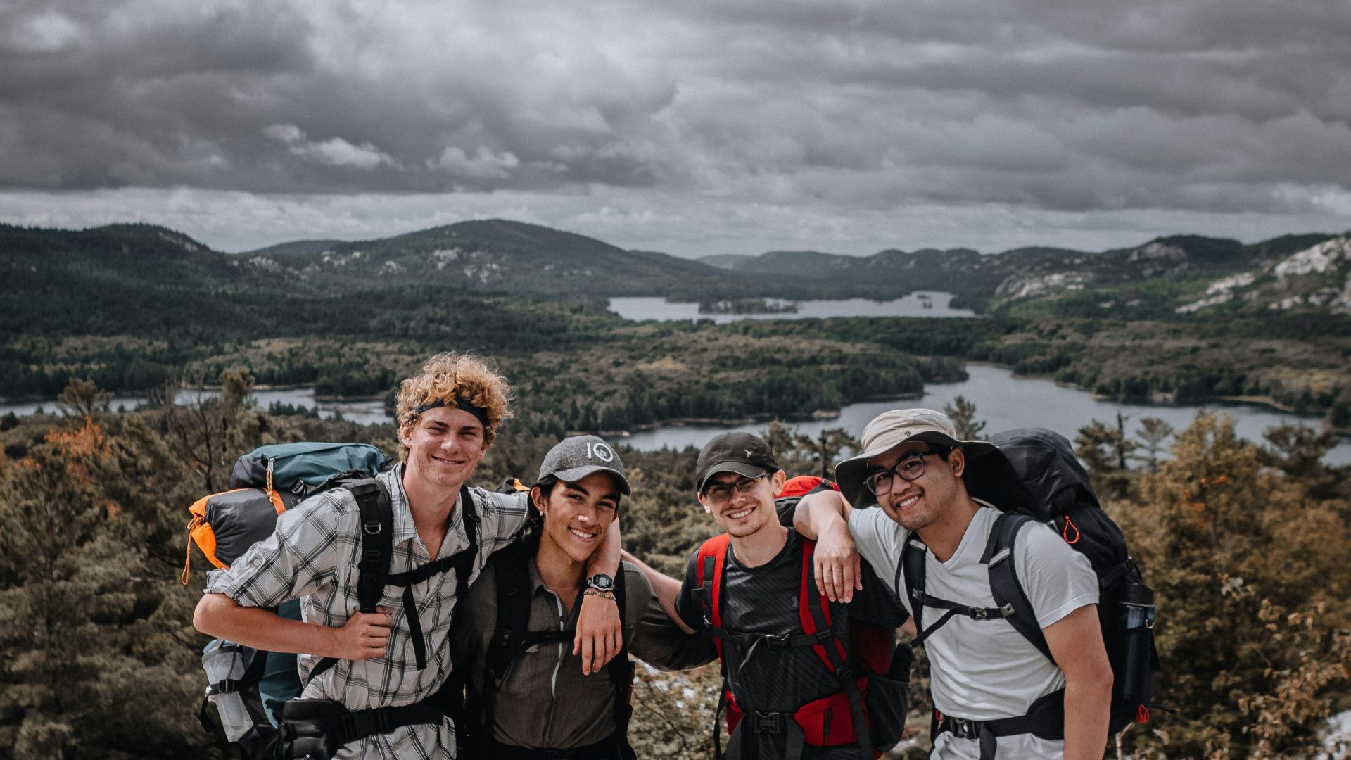 3 men standing on rocky mountain during daytime