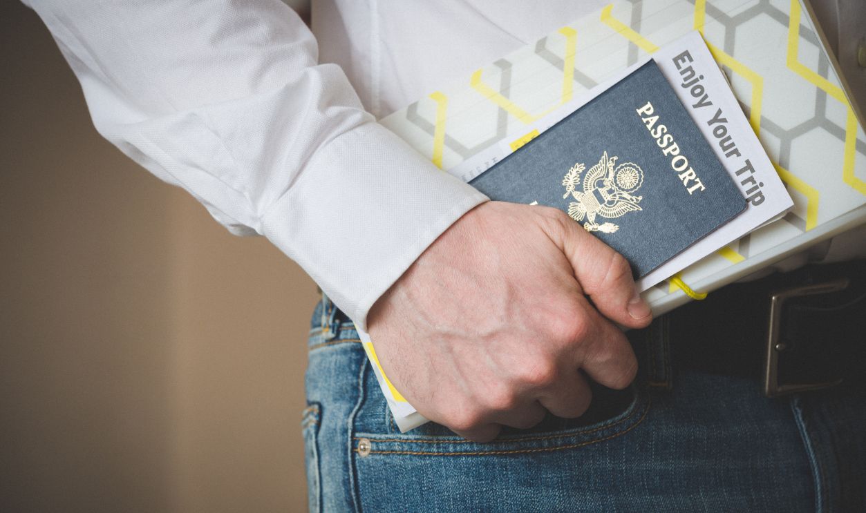 American passport in the hand of a young man. Passport and travel documents. Waiting for a flight at the airport at customs or passport control. Business trip. Open world.