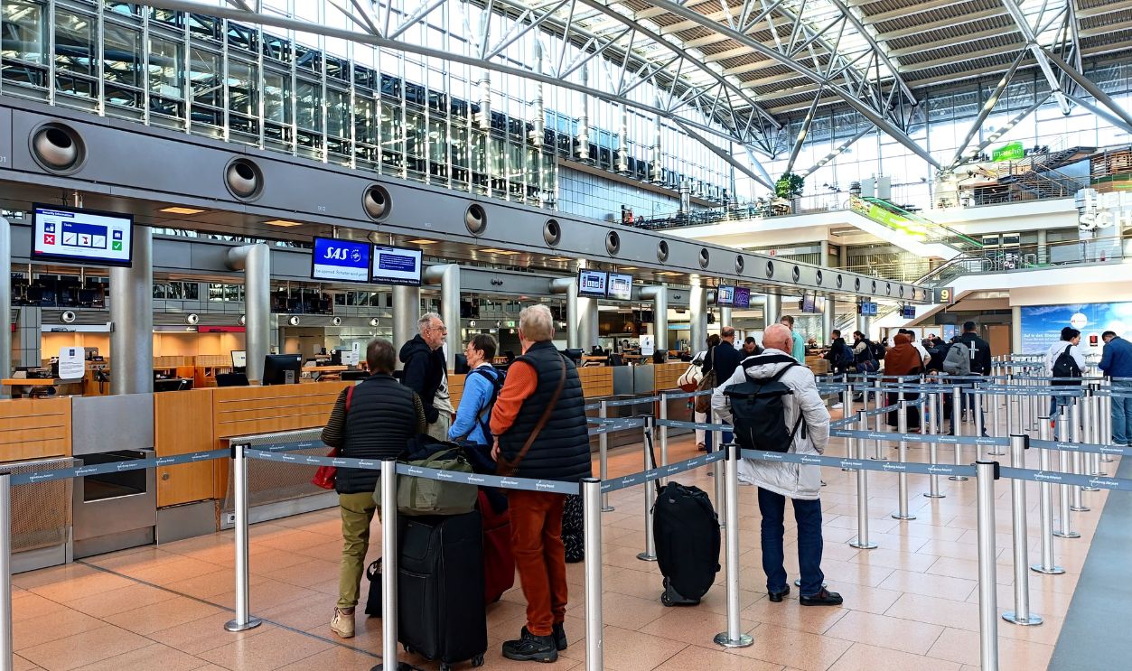 Travelers in line at Hamburg Airport's check-in counters, showcasing modern architecture