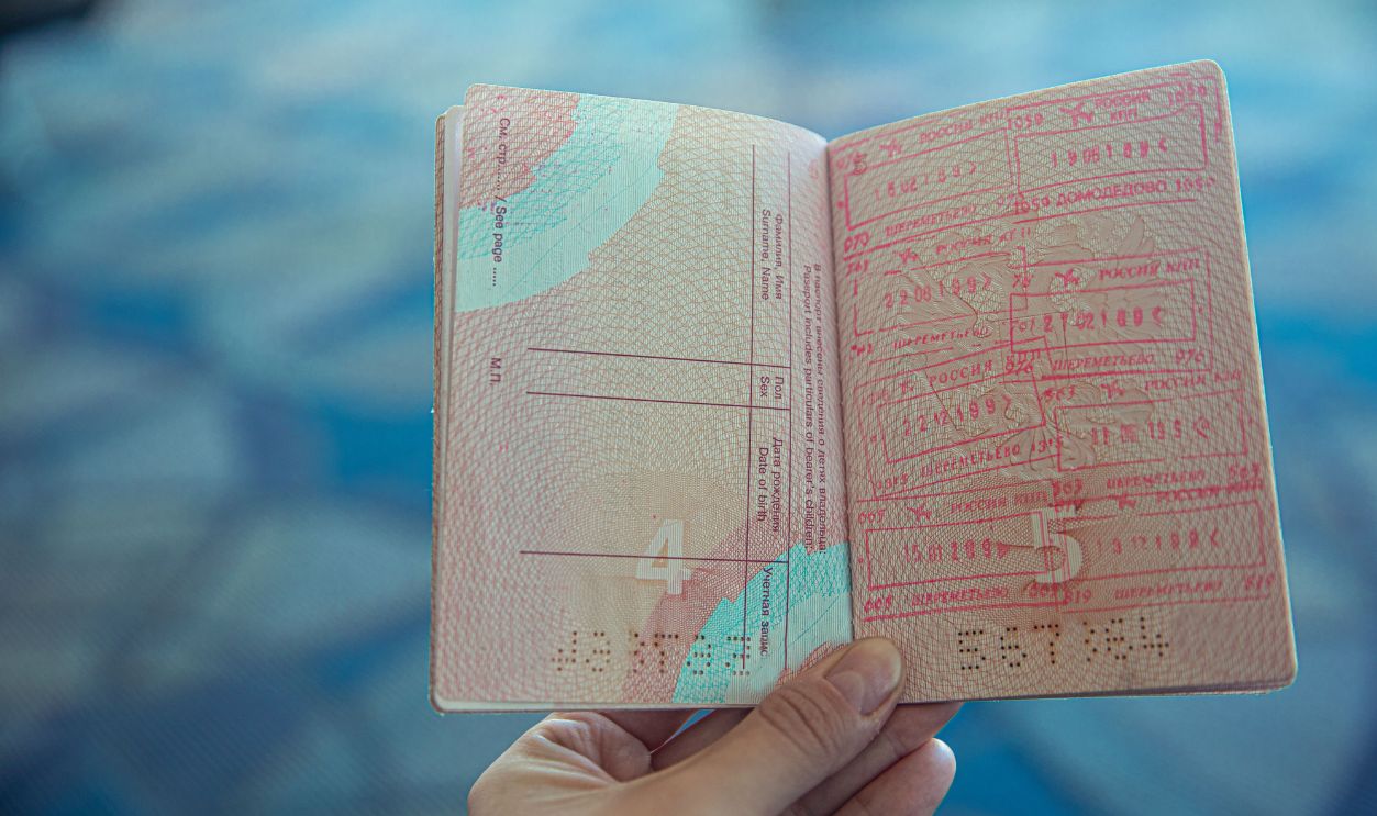 Close-up view of an open passport displaying various travel stamps in an airport setting