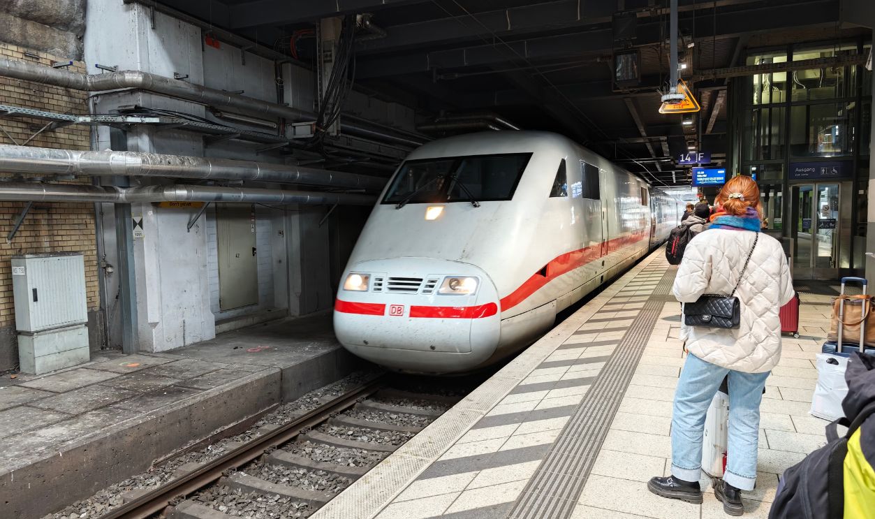 Modern high-speed train approaches station platform with passengers waiting, showcasing urban travel