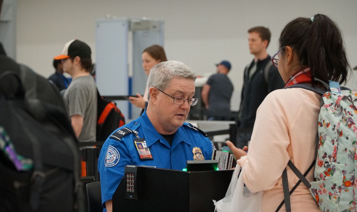 Shutterstock-1641623299, Baltimore, MD, USA - April 8 2019: TSA (Transportation Security Administration) worker checks out passport at the BWI airport.