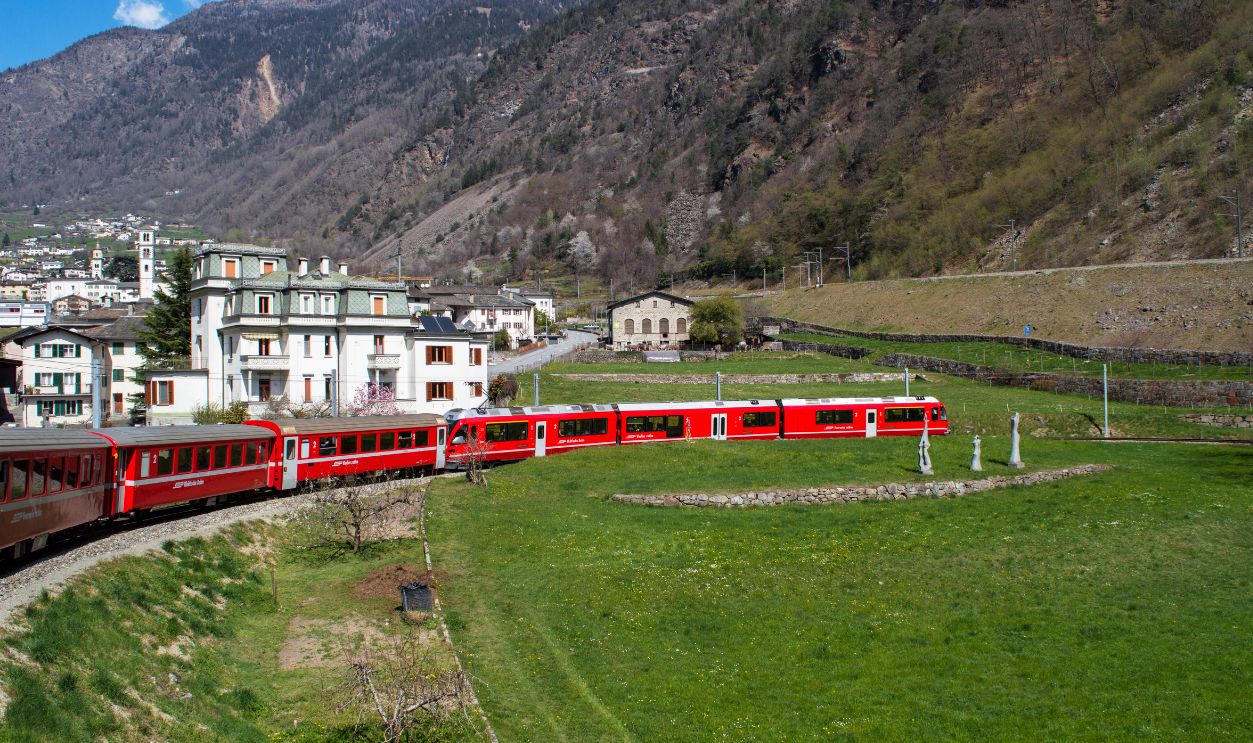 The iconic red Bernina Express train traverses a scenic valley in the Swiss Alps