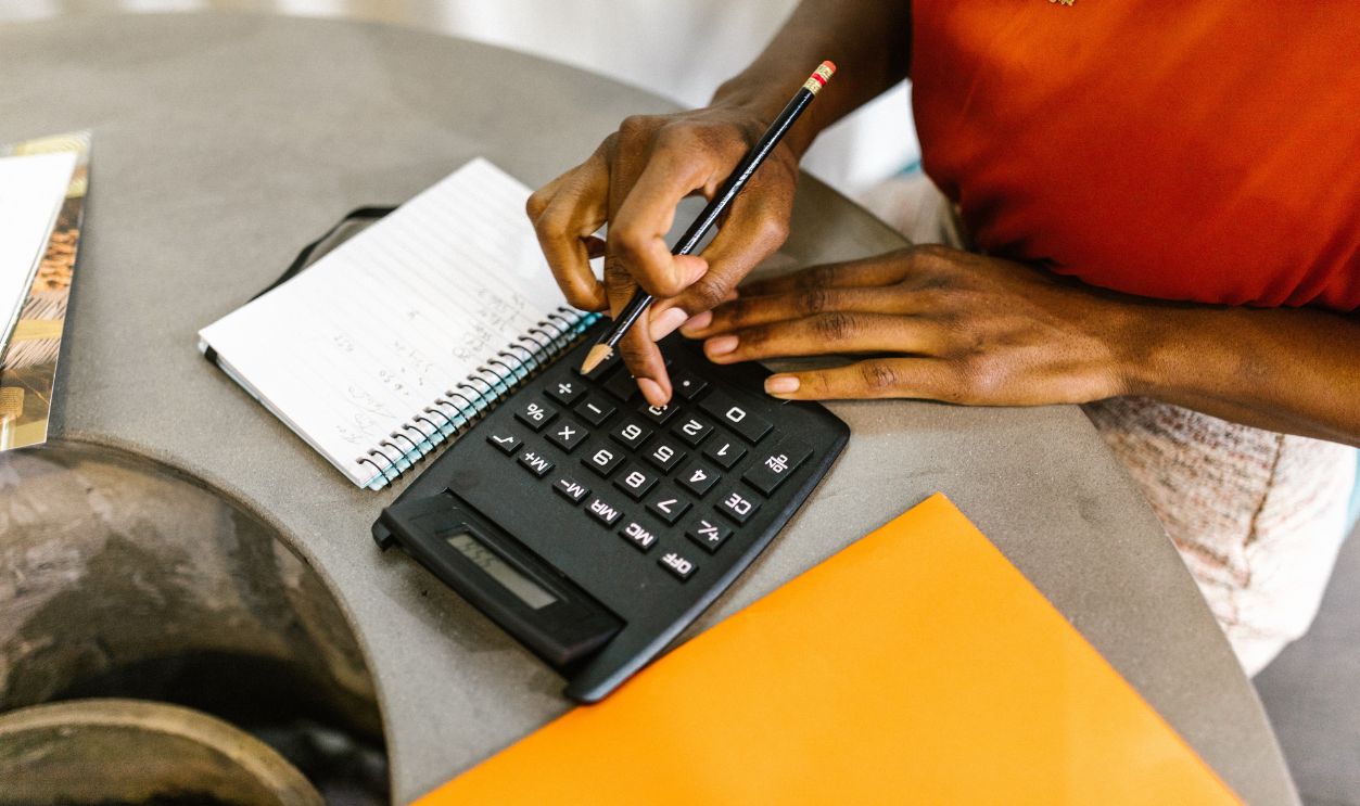 An African American woman using a calculator and notepad for budgeting
