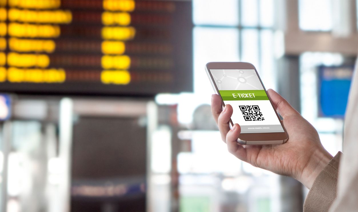Buying online ticket from internet. E-ticket on mobile phone screen with schedule in the blurred background. Universal public transportation terminal. Bus, train, metro, subway or underground station
