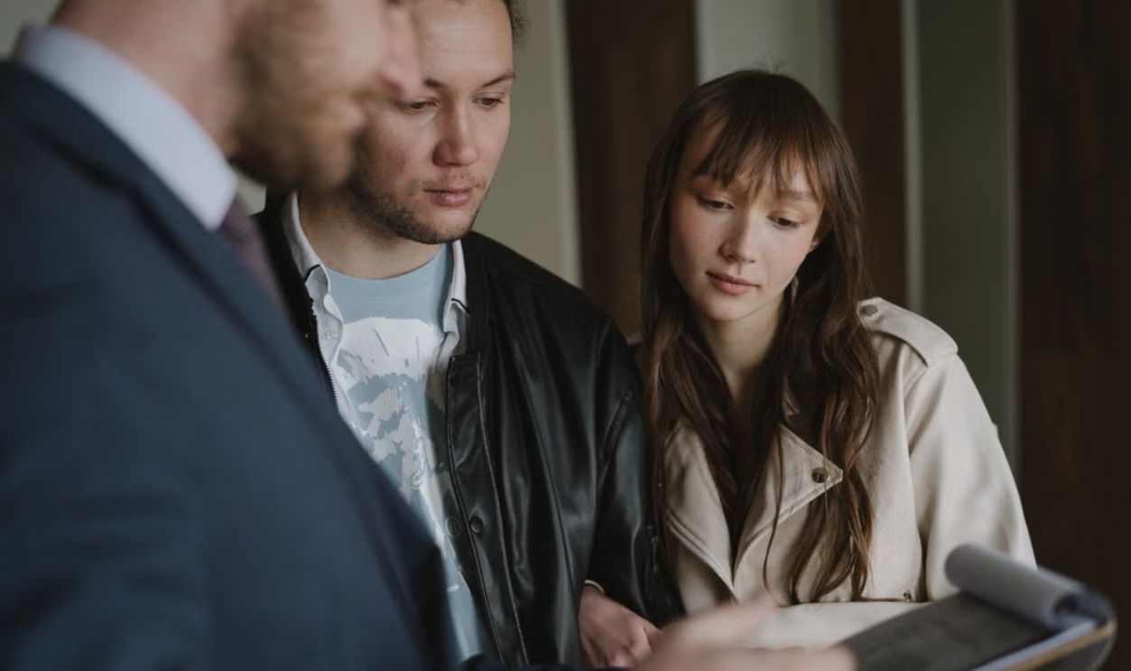 A couple discusses home buying details with a realtor inside a modern apartment