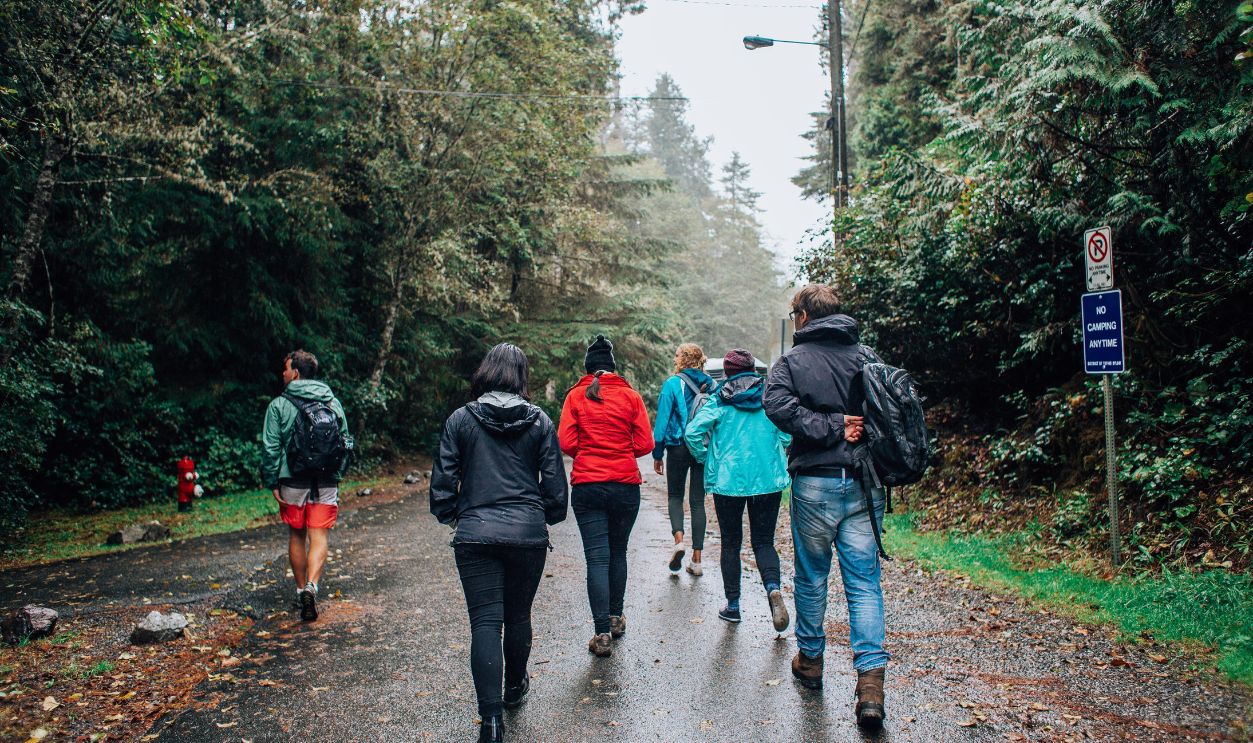 A group of hikers walking on a wet forest trail