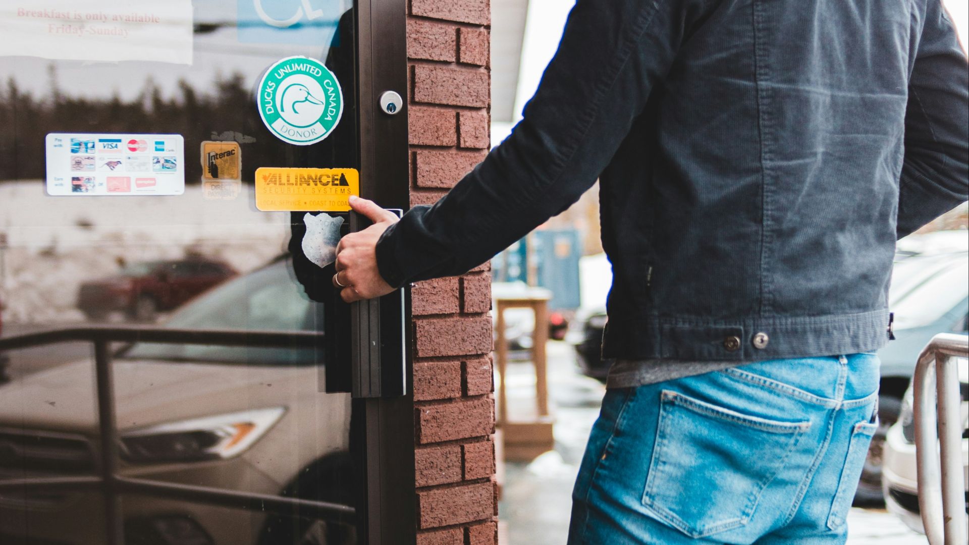 man in black long sleeve shirt and blue denim jeans holding yellow and white labeled box
