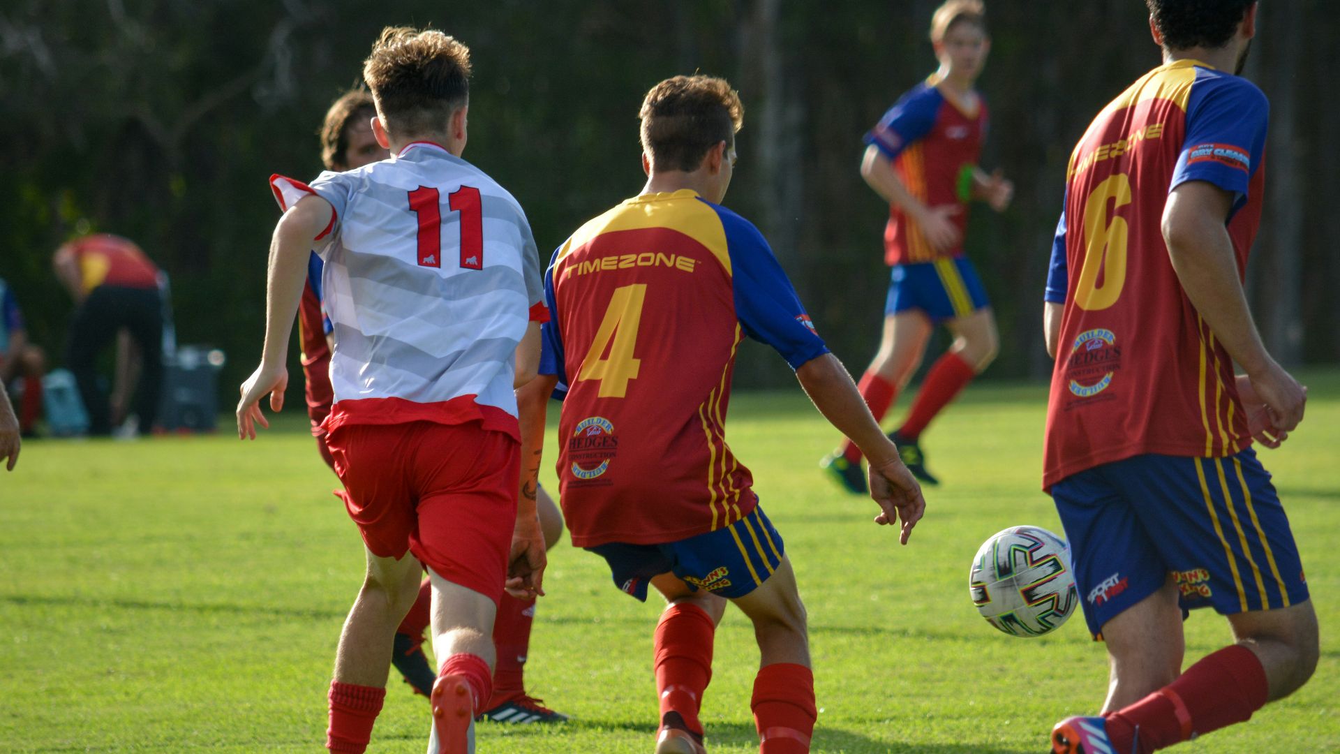men in red and blue soccer jersey shirt running on green grass field during daytime
