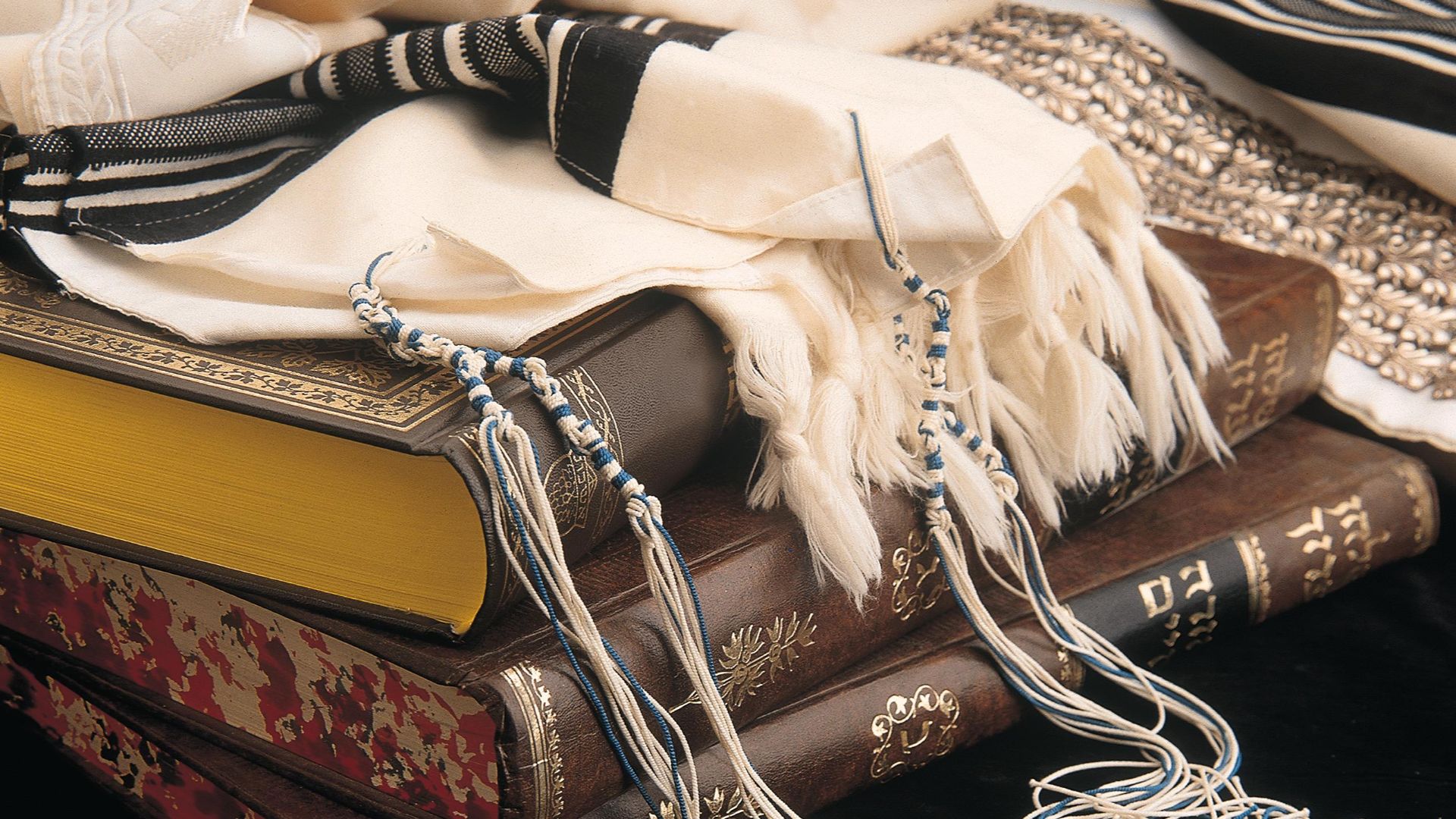 Tallit with tekhelet strings, resting on volumes of the Shulchan Aruch
