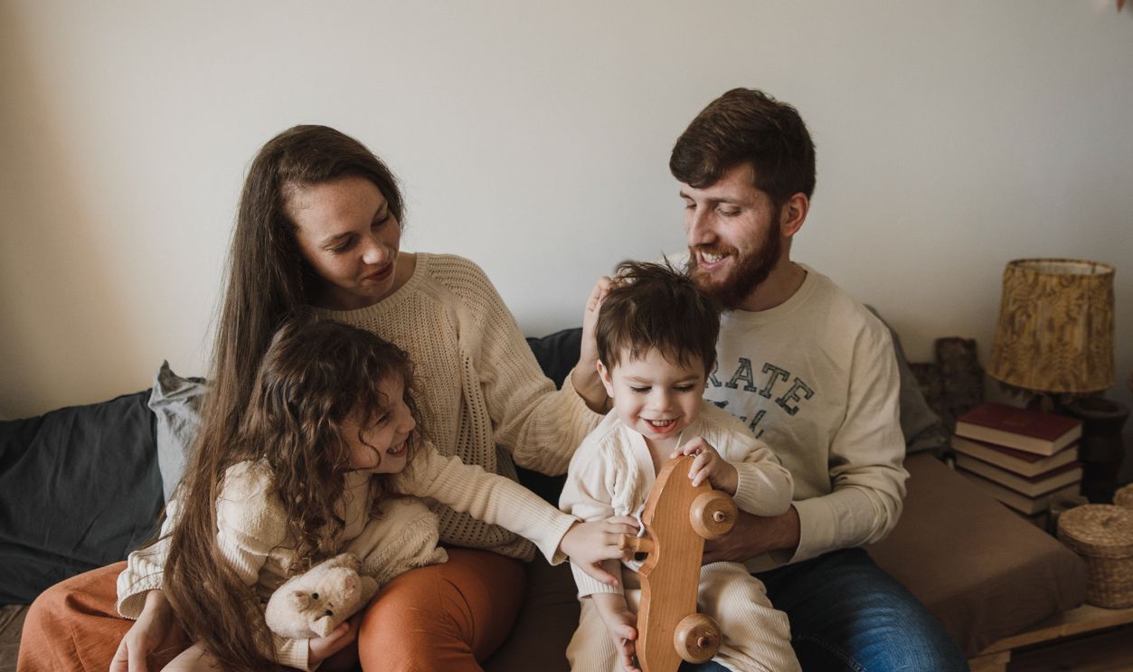 A joyful family of four sitting together on a sofa, enjoying their time