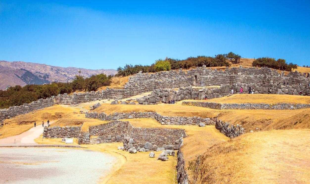 Explore the ancient stone ruins of Sacsayhuaman under a clear blue sky in Cusco, Peru