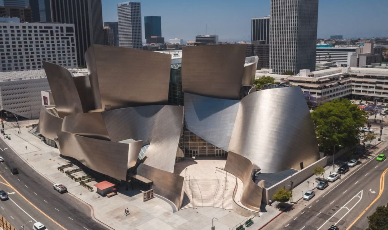 A stunning aerial view of the iconic Walt Disney Concert Hall in Los Angeles against a backdrop of urban skyscrapers