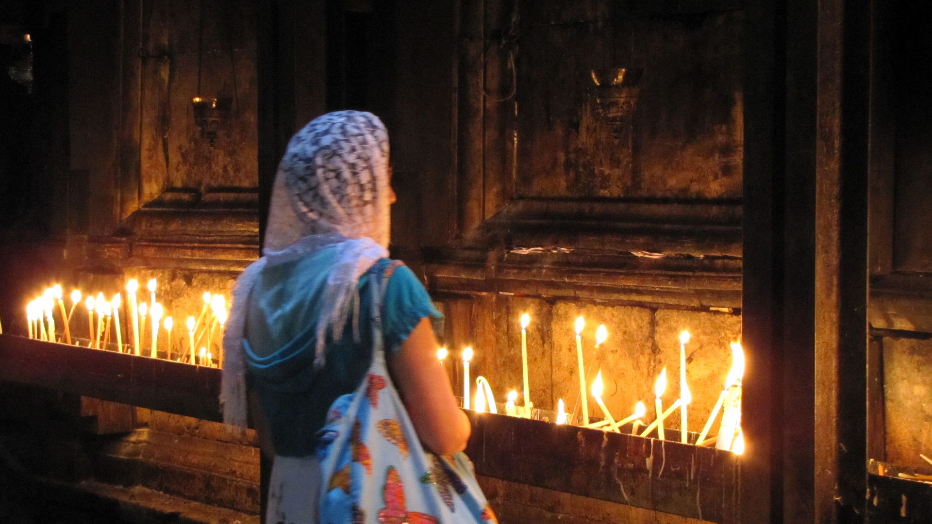 Votive candles on the metal shoring of the Aedicule.