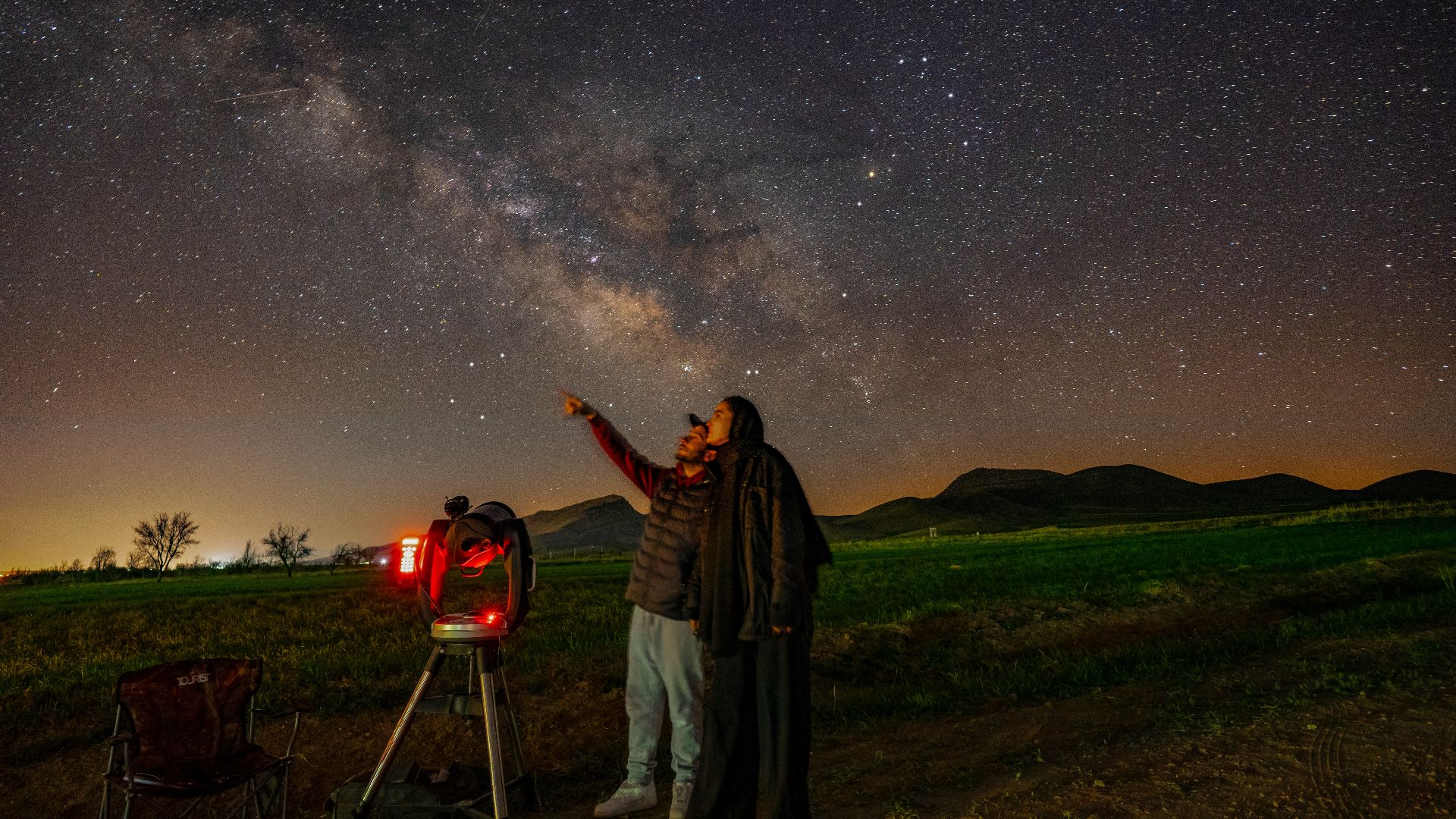 a man standing next to a telescope looking at the stars