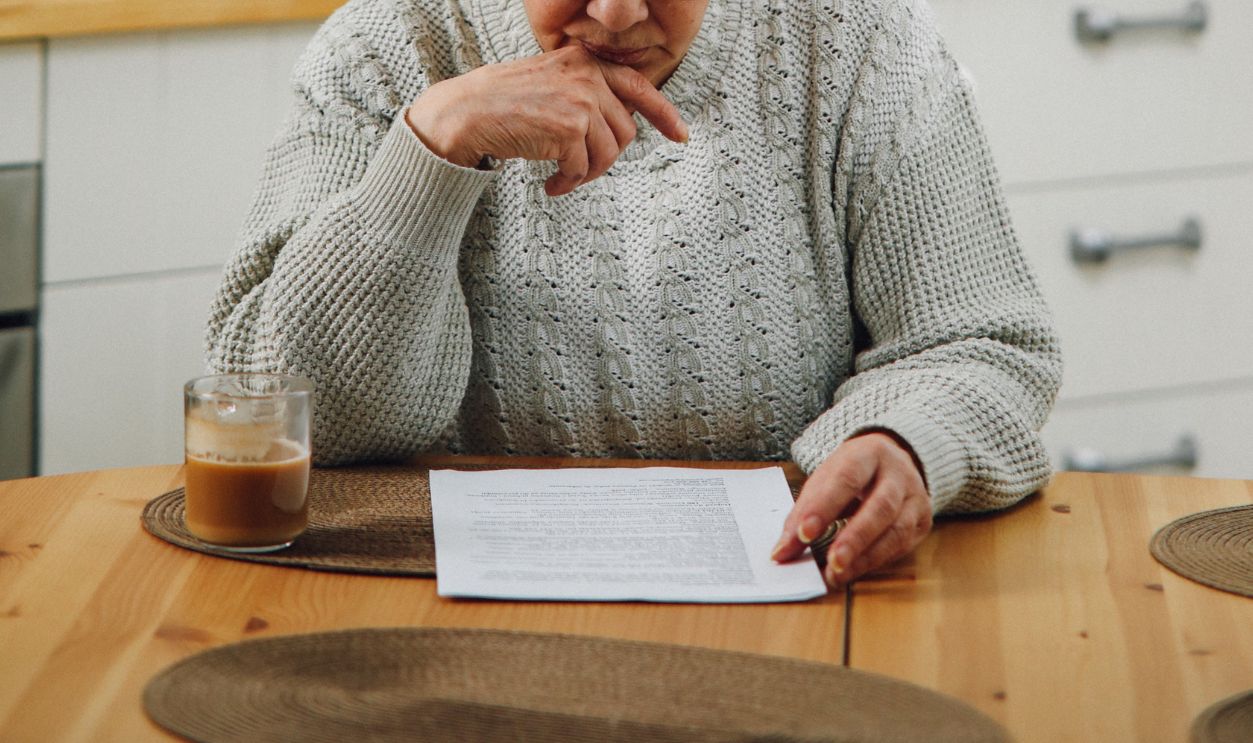 Senior woman reading at a kitchen table, deep in thought